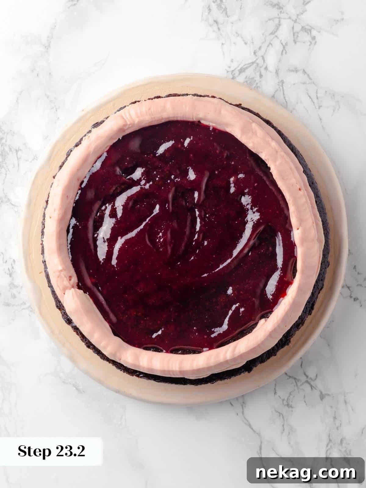 The first cake layer topped with a dam of raspberry buttercream and a generous spread of raspberry jam, ready for the next layer.