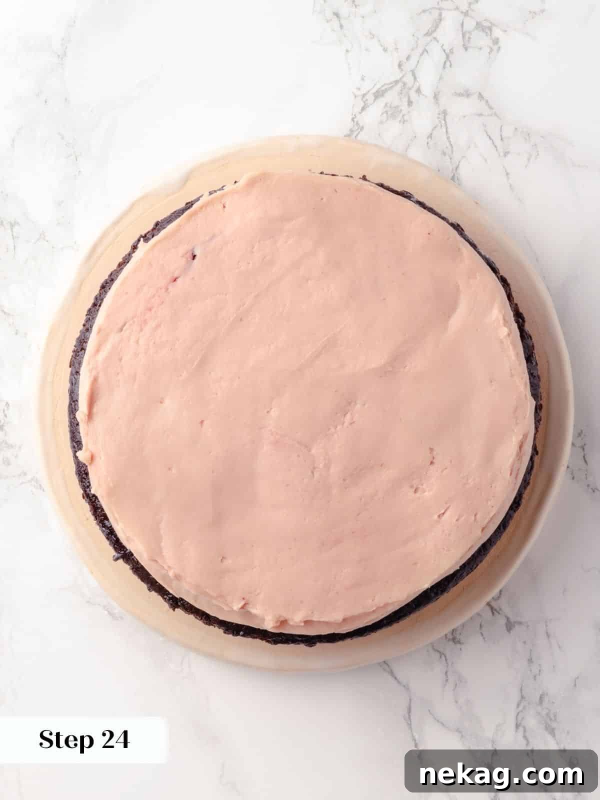 Buttercream smoothed over a layer of raspberry jam on the cake, creating an even surface for the next layer.
