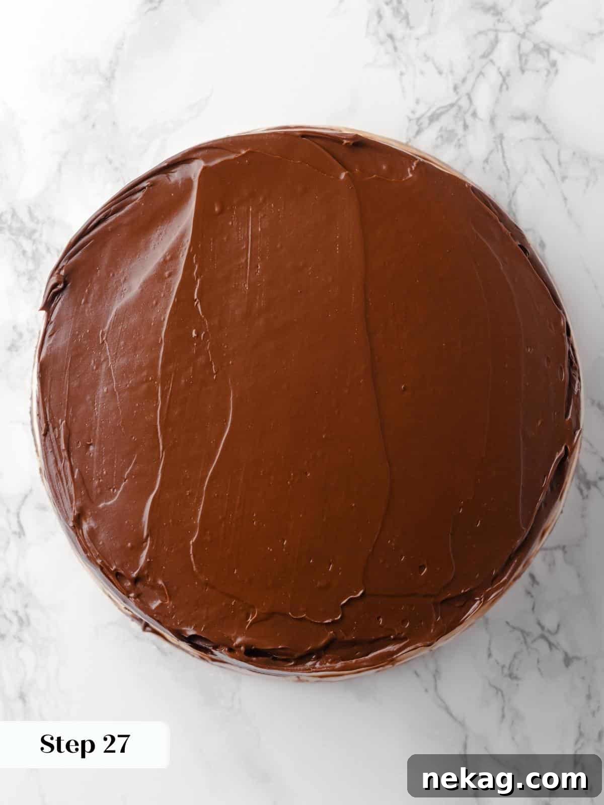 Chocolate frosting smoothed onto the top layer of the cake with a spatula, creating a seamless, dark surface.