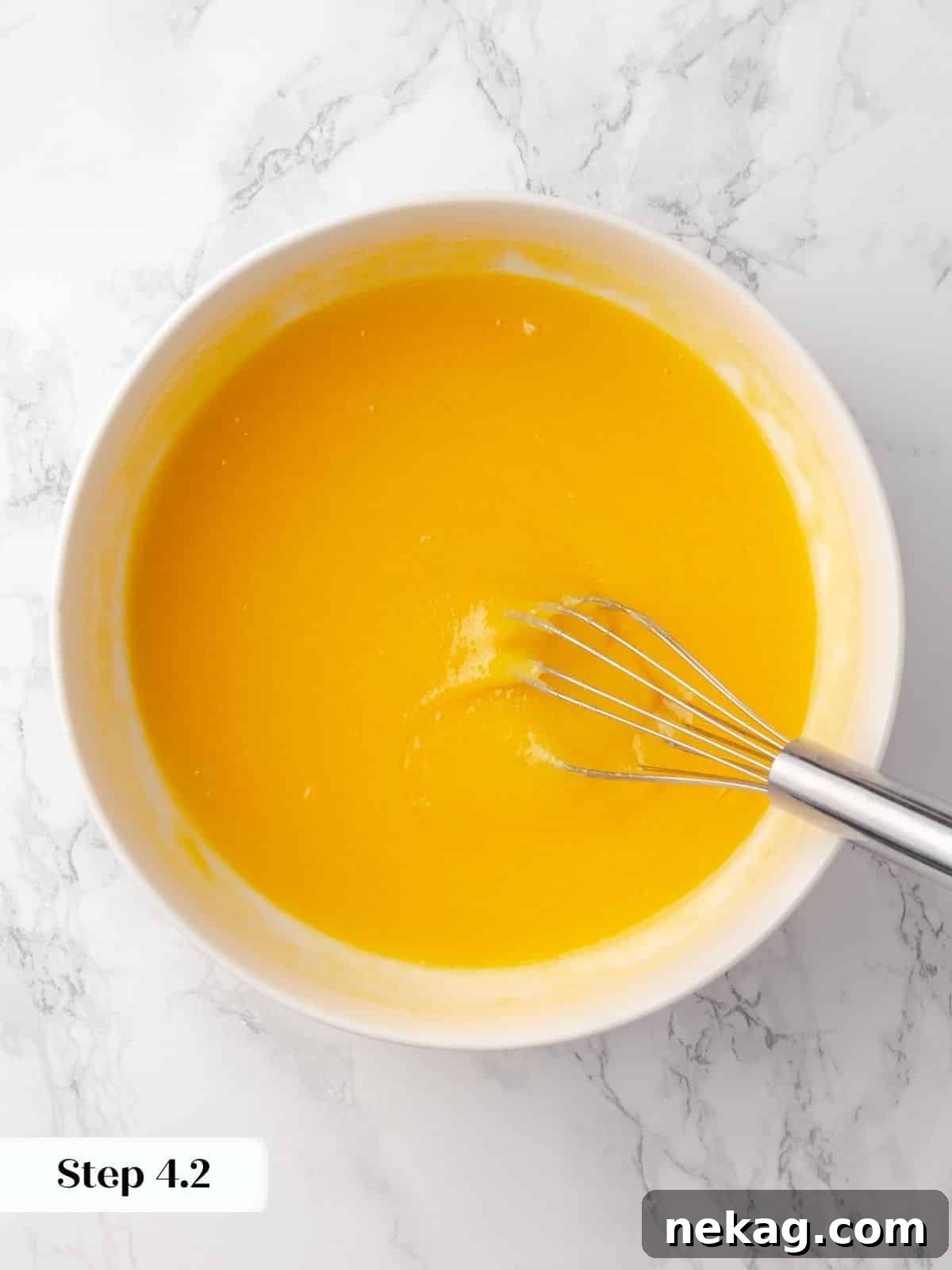 Sugar being mixed with eggs in a bowl, creating a smooth base for the cake batter, glossy and well-combined.