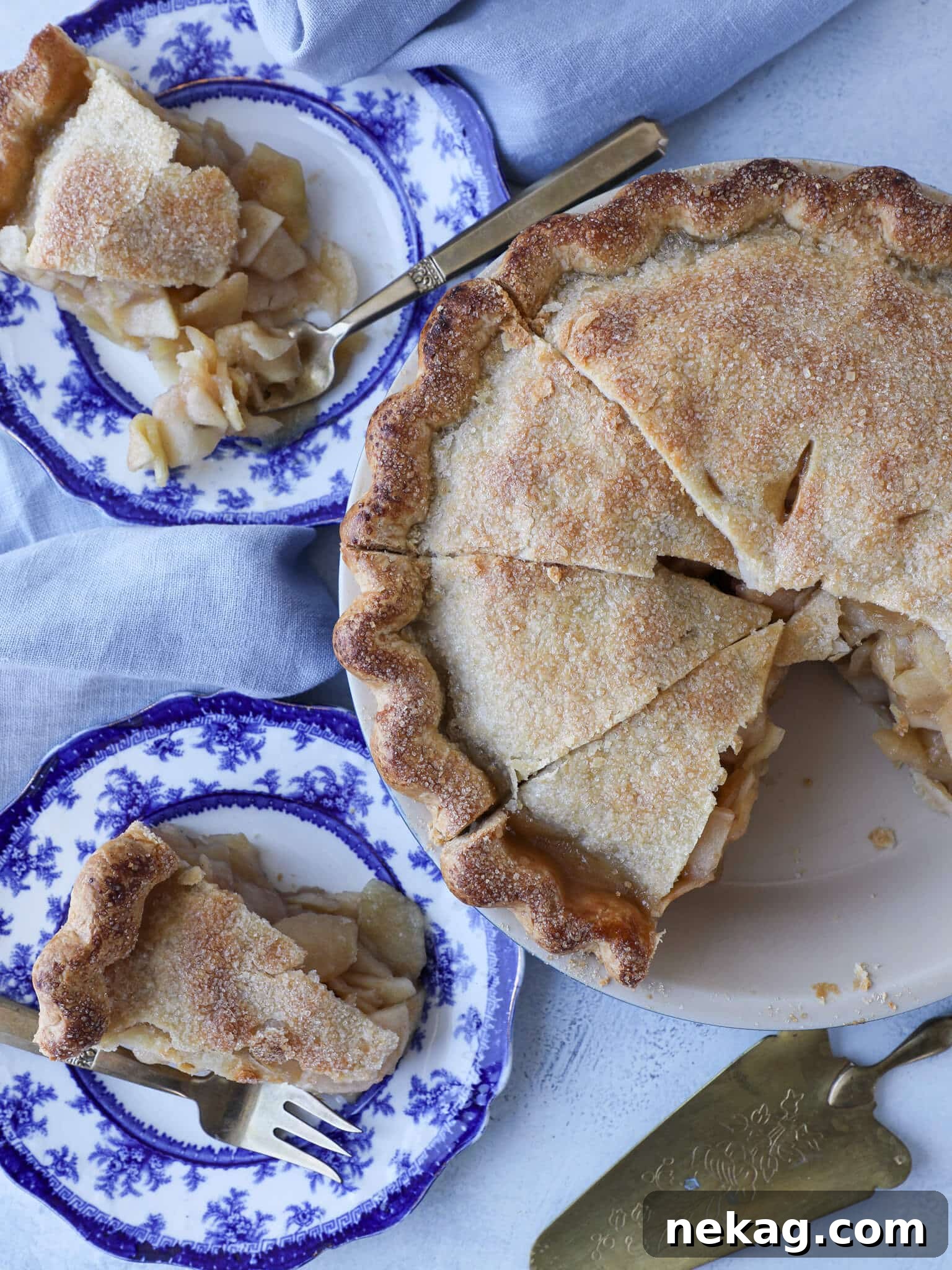 A beautifully set tablescape featuring a slice of golden-brown Mile High Apple Pie, ready to be served.