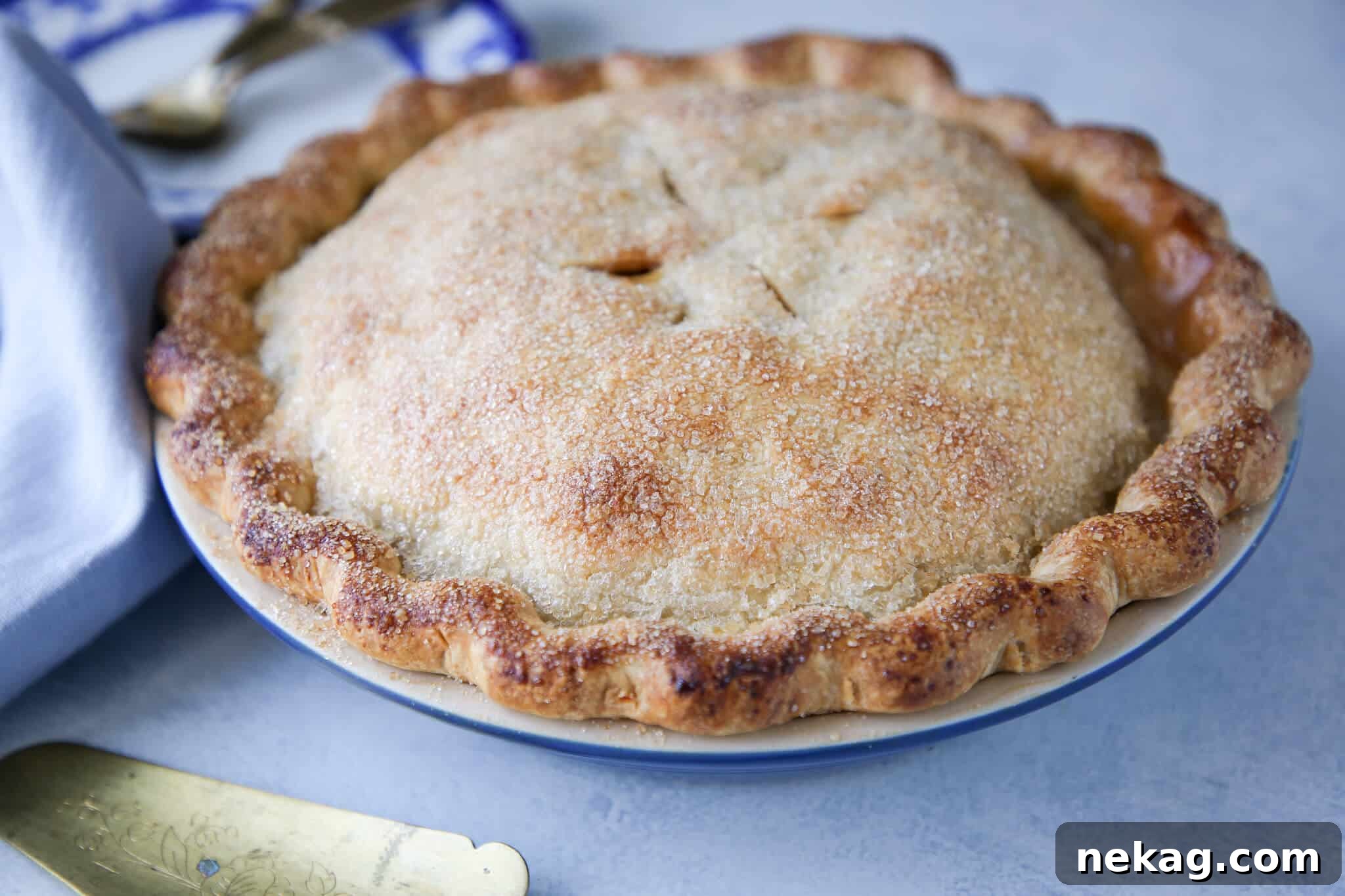 An unsliced, golden-brown Double Crusted Fruit Tart, perfectly baked and ready for slicing, with a decorative crust.