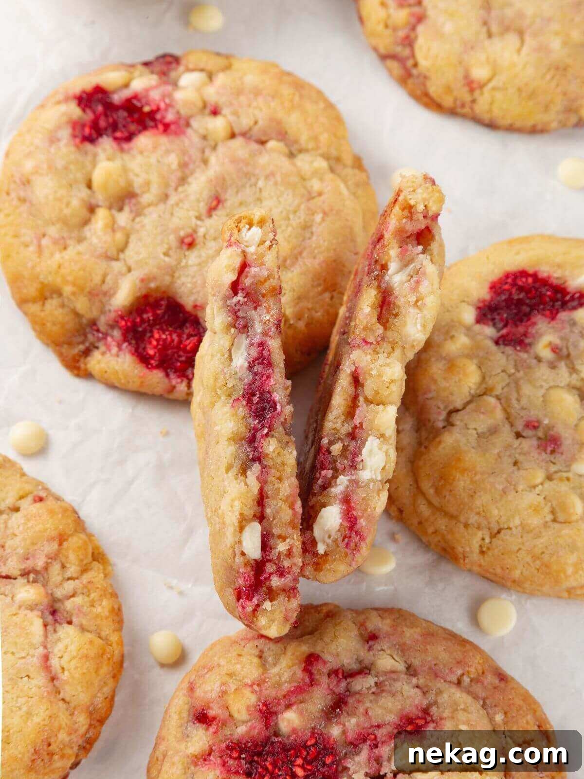 A close-up of a white chocolate raspberry cookie with a chewy, soft interior and melted chocolate.