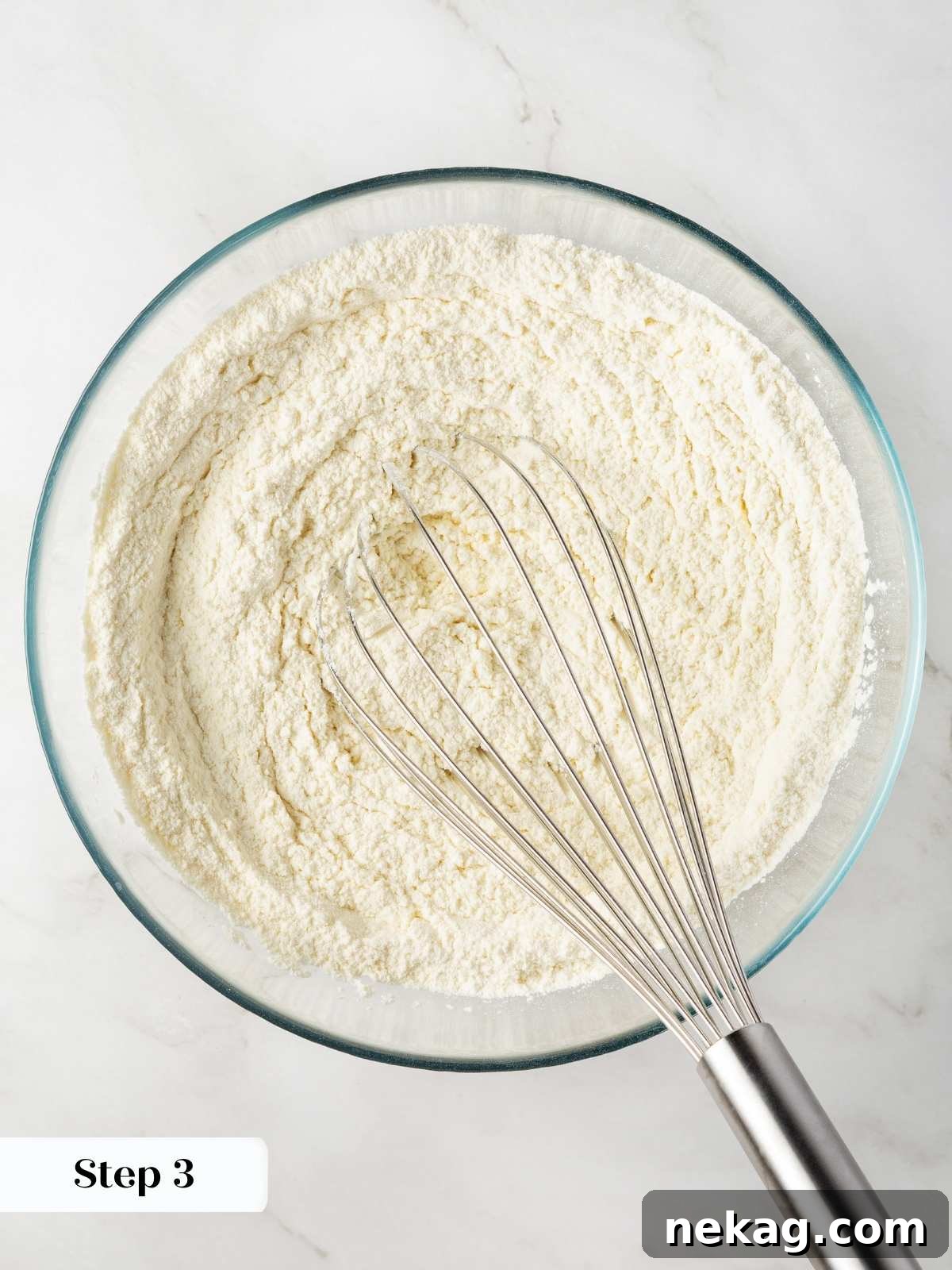 Dry ingredients being whisked together in a bowl to ensure even distribution in the cookie dough.