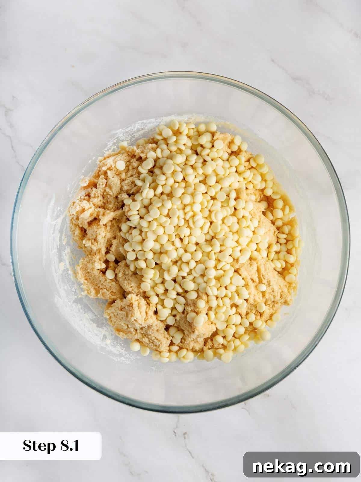 White chocolate chips being added to the cookie dough for a creamy, sweet flavor.