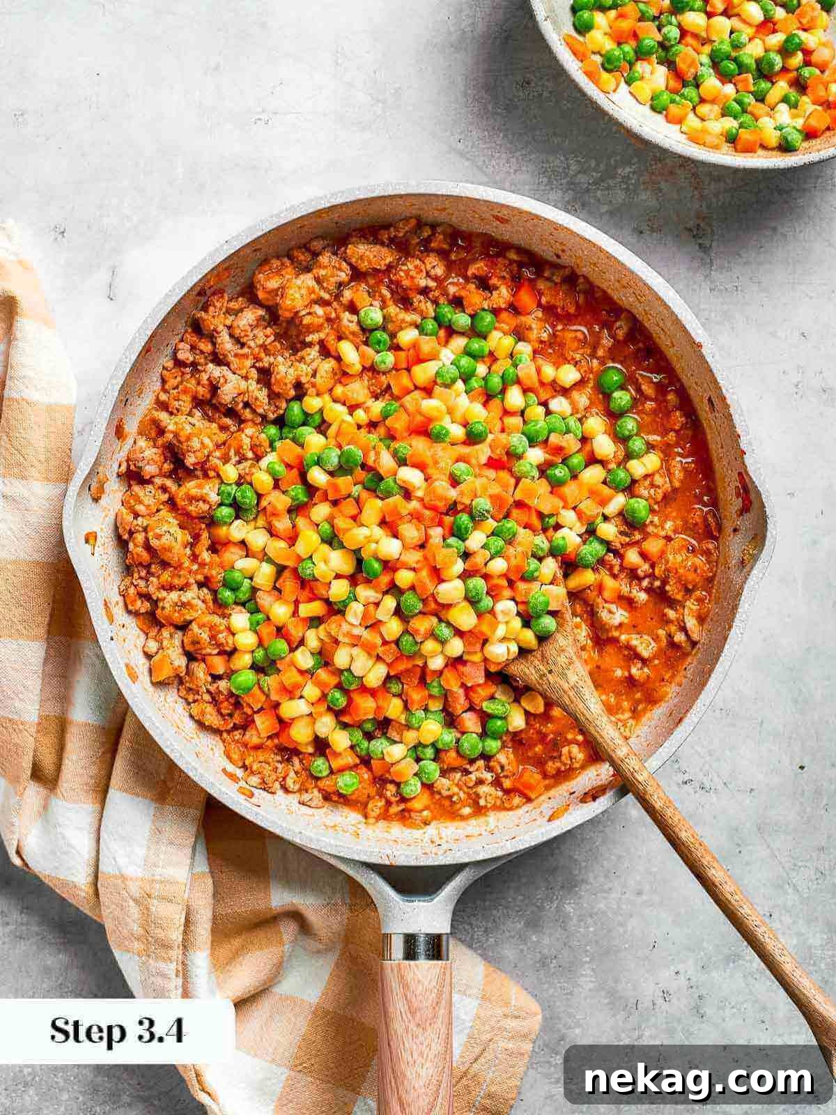 A medley of colorful frozen vegetables, including peas, carrots, and corn, freshly added to the simmering chicken skillet, bringing texture and flavor.