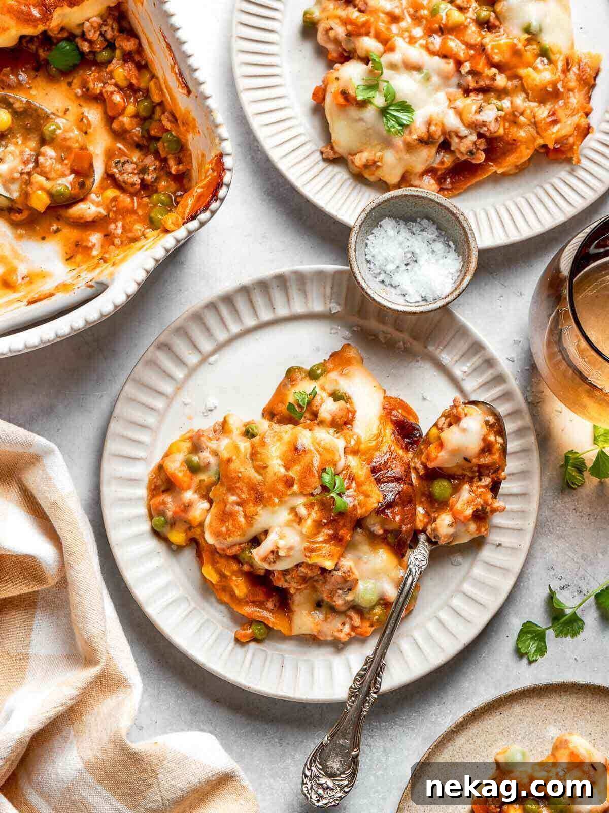 A generous, perfectly scooped serving of Chicken Shepherd’s Pie on a pristine white plate, showcasing the distinct layers of savory chicken, vibrant vegetables, and fluffy mashed potatoes.