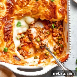 A rustic white baking dish filled with a comforting Chicken Shepherd’s Pie, featuring a perfectly browned mashed potato topping, ready for serving.