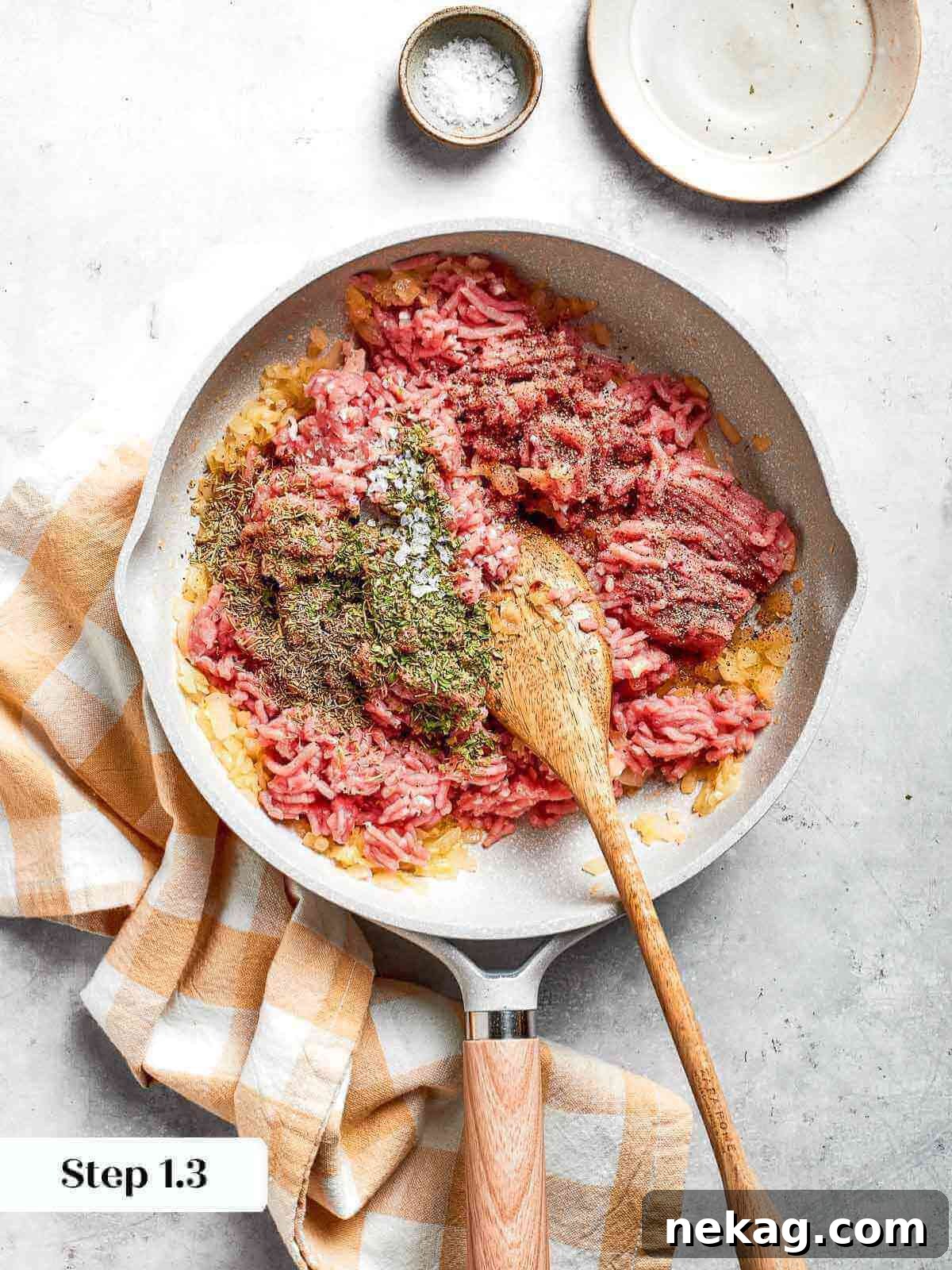A close-up of fragrant dried herbs, including thyme, rosemary, and parsley, being sprinkled into the skillet with the browning chicken and aromatics.