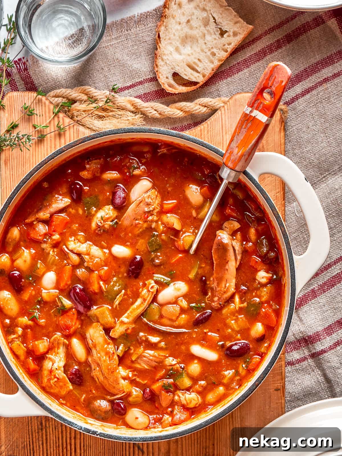A rich, red-broth chicken vegetable soup, served in a rustic bowl.