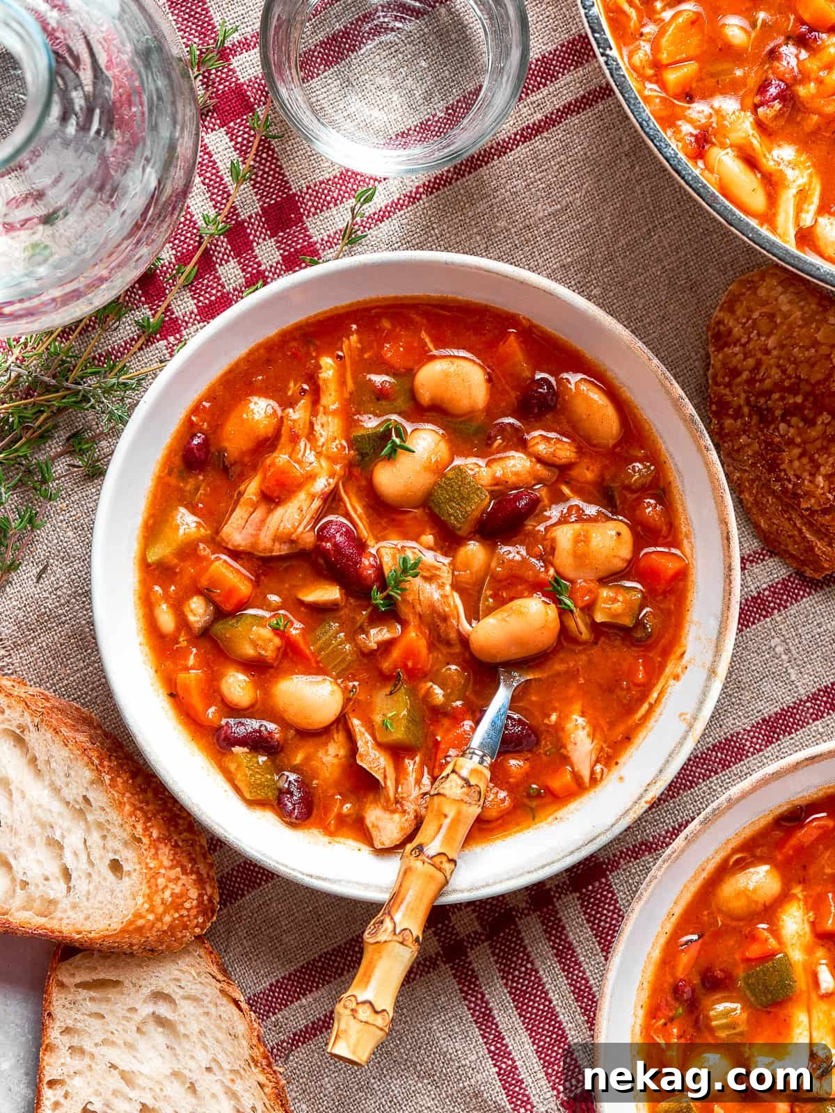 A spoonful of chicken and vegetables being lifted from a soup bowl.