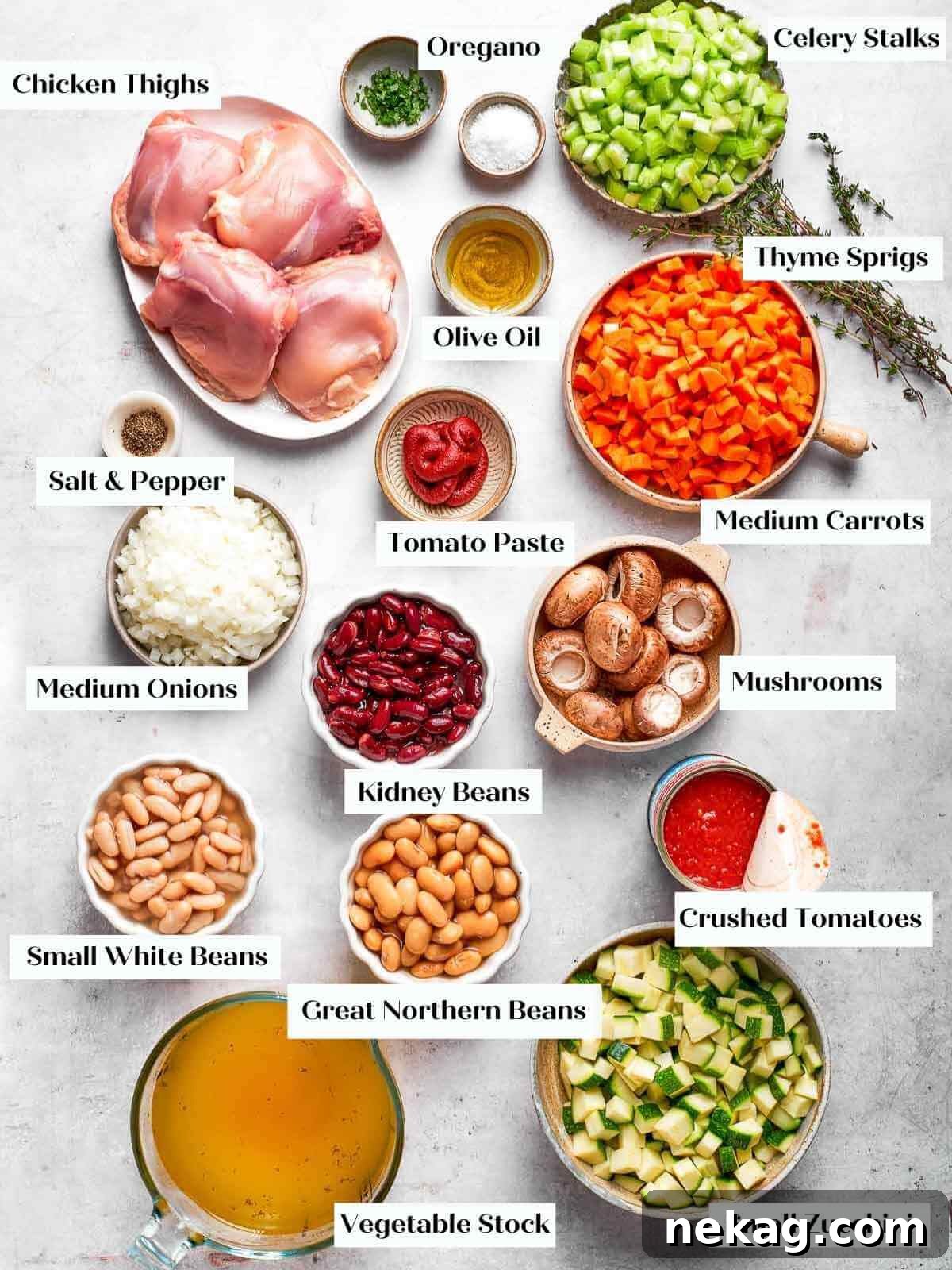 All fresh ingredients for the chicken vegetable soup arranged on a white marble countertop.
