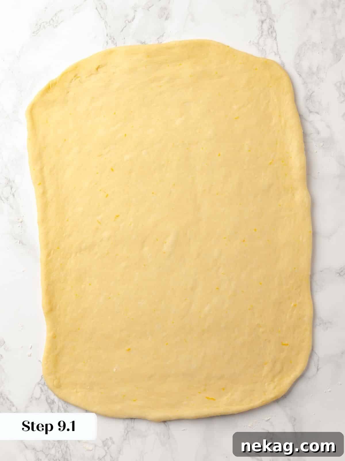 Sticky bun dough rolled into a large rectangle on a floured surface.