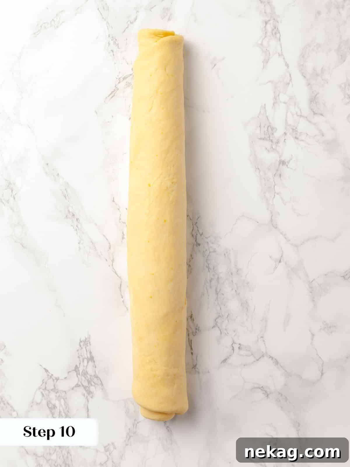 Cinnamon-filled sticky bun dough rolled into a tight log before cutting.