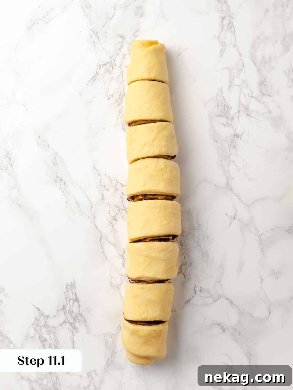 A rolled log of sticky bun dough sliced into even pieces.