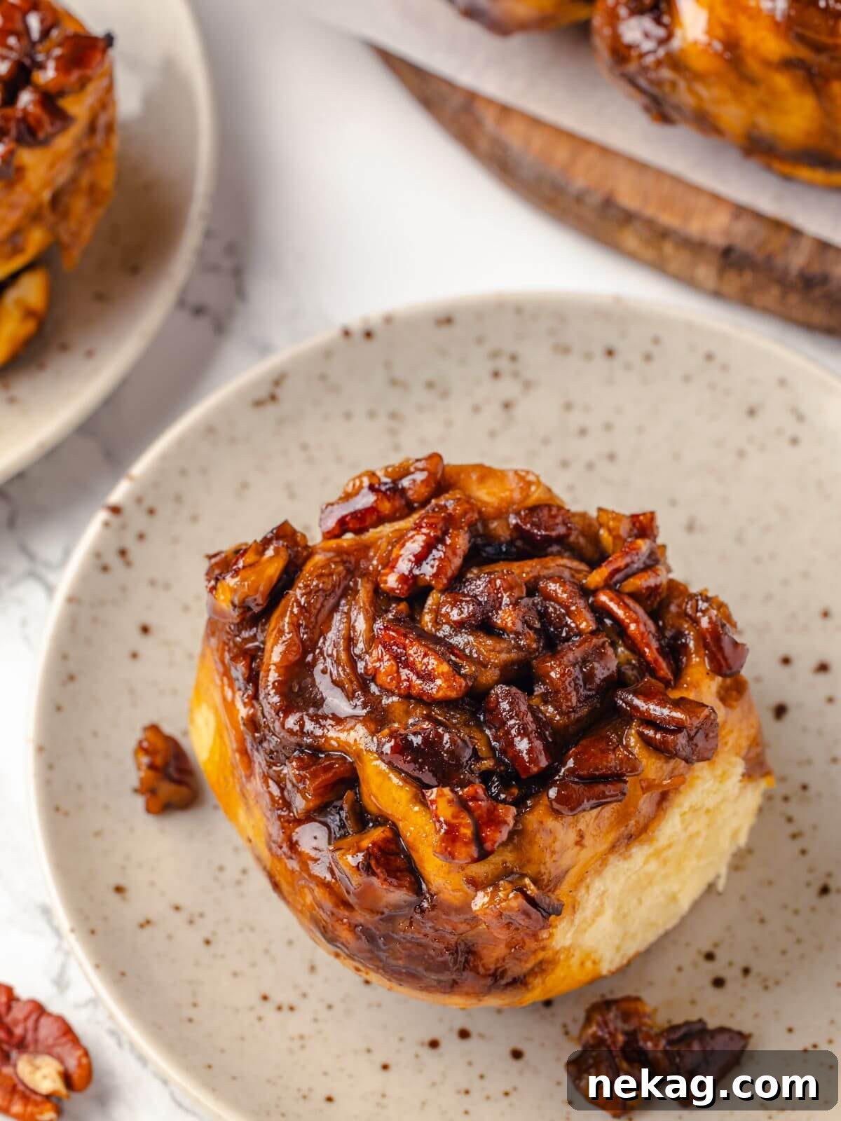 Close-up of a single pecan sticky bun showing its gooey topping.