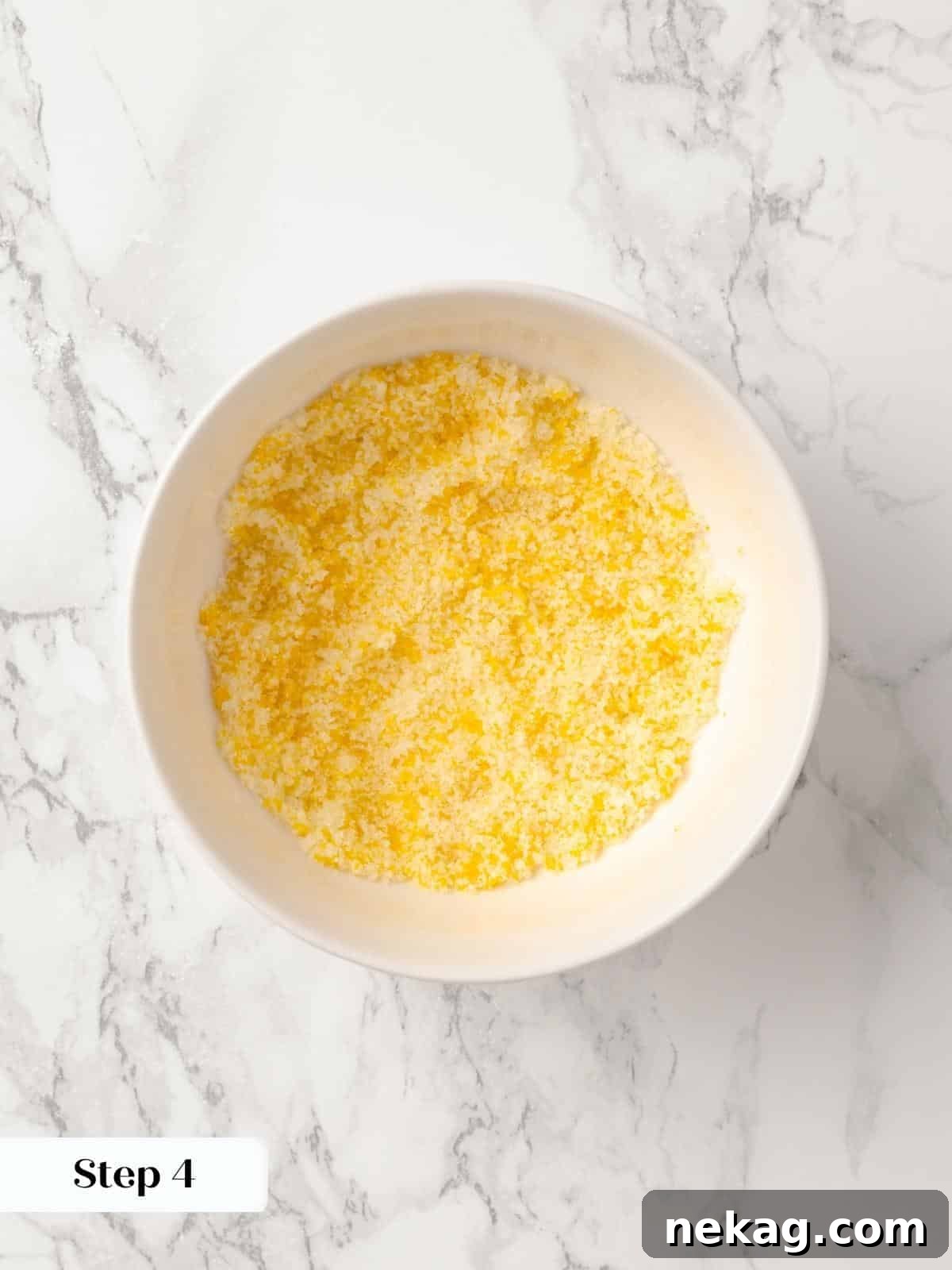 A small bowl of sugar and orange zest being combined.