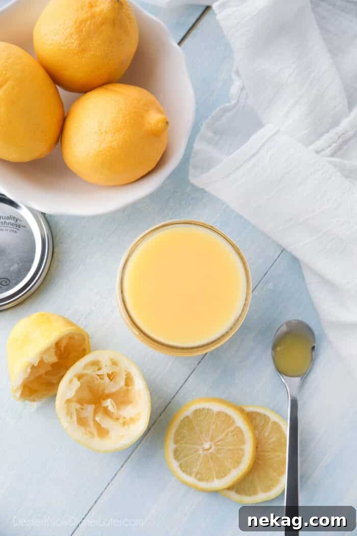 Homemade Lemon Curd Delight 4 A jar of homemade lemon curd, surrounded by whole lemons, halves of juiced lemons, and decorative lemon slices, emphasizing freshness.