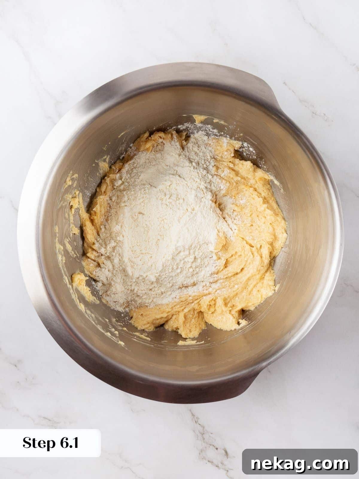 Flour mixture being poured into the wet ingredients in a mixing bowl for incorporation.