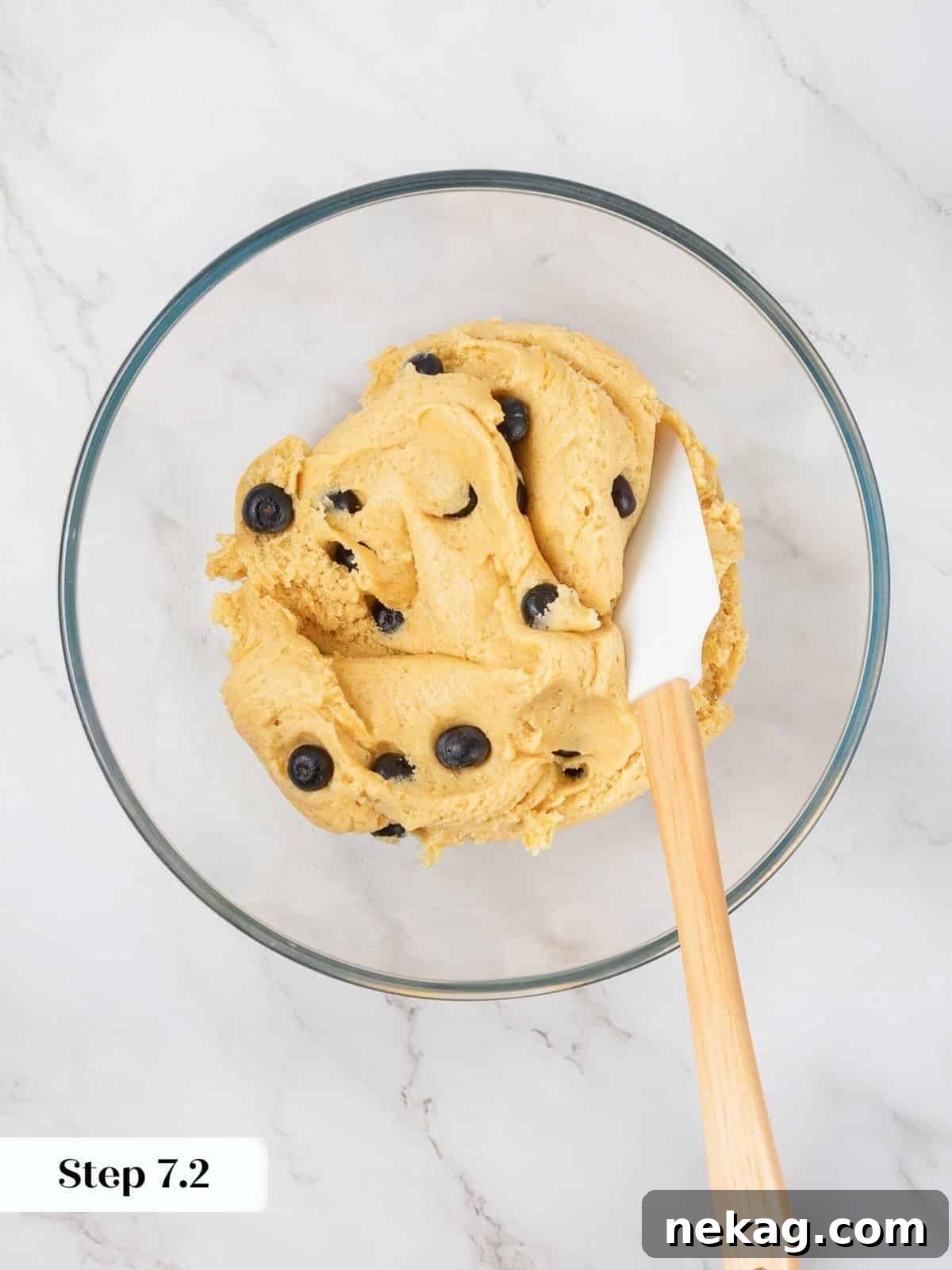 Cookie dough fully mixed with whole blueberries evenly distributed, ready for portioning.