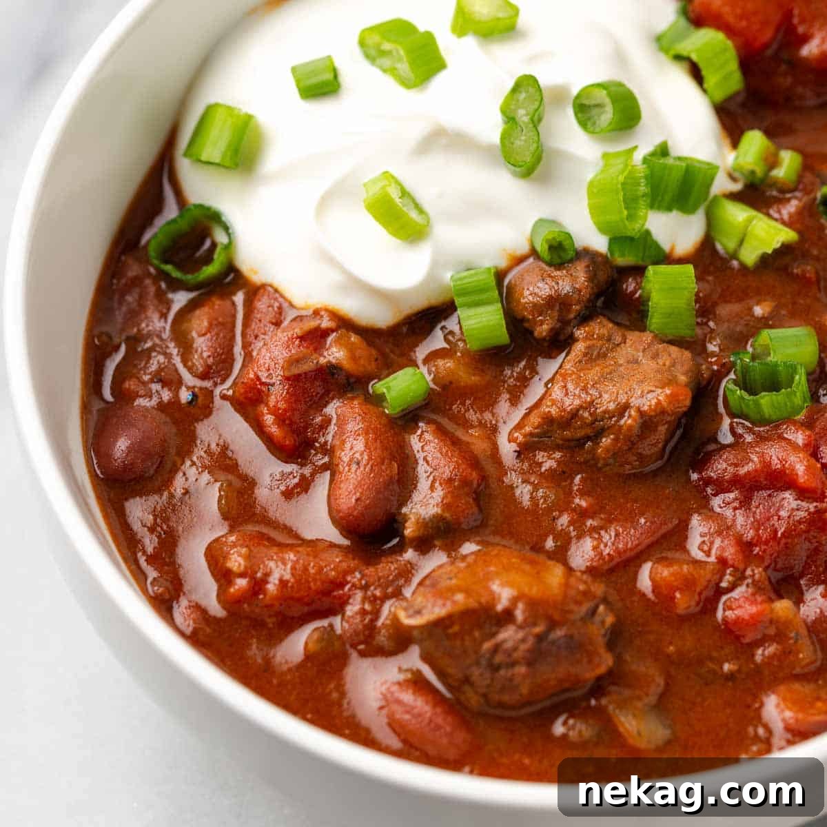 A beautifully presented bowl of rich steak chili garnished with fresh herbs, showcasing its deep color and hearty texture.