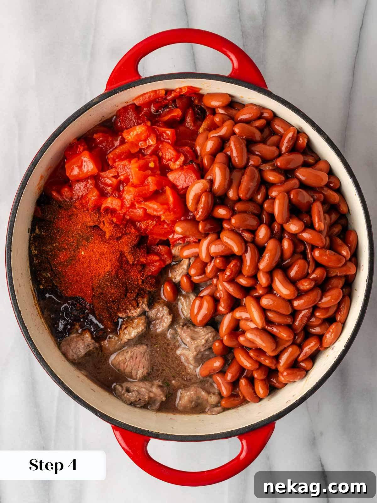 All chili ingredients (beef, beans, tomatoes, and spices) combined in a large pot, stirred and ready to simmer.
