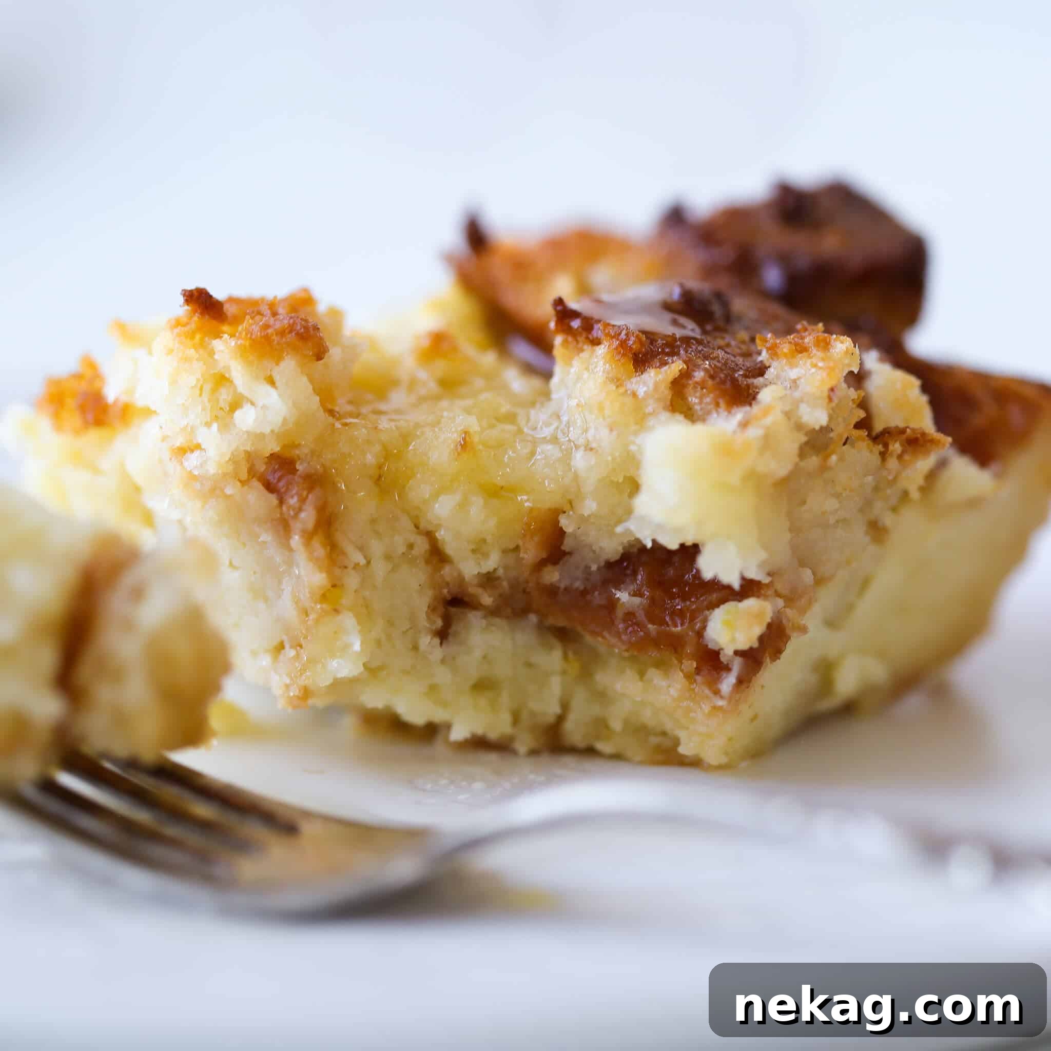 A close-up view of a single slice of Lemon Raspberry Bread Pudding on a white plate