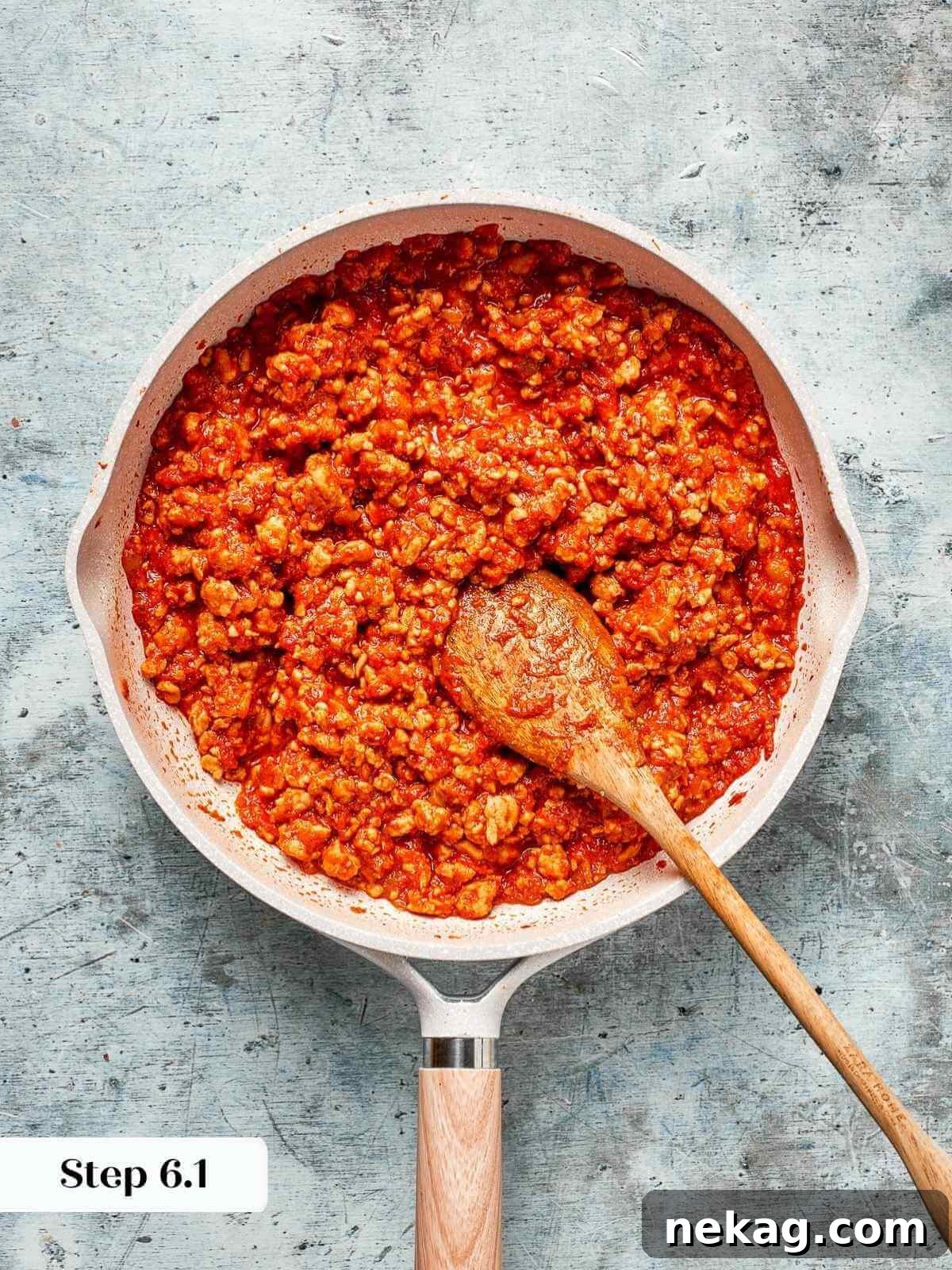 The sloppy joe mixture actively simmering on the stovetop, bubbling and thickening.