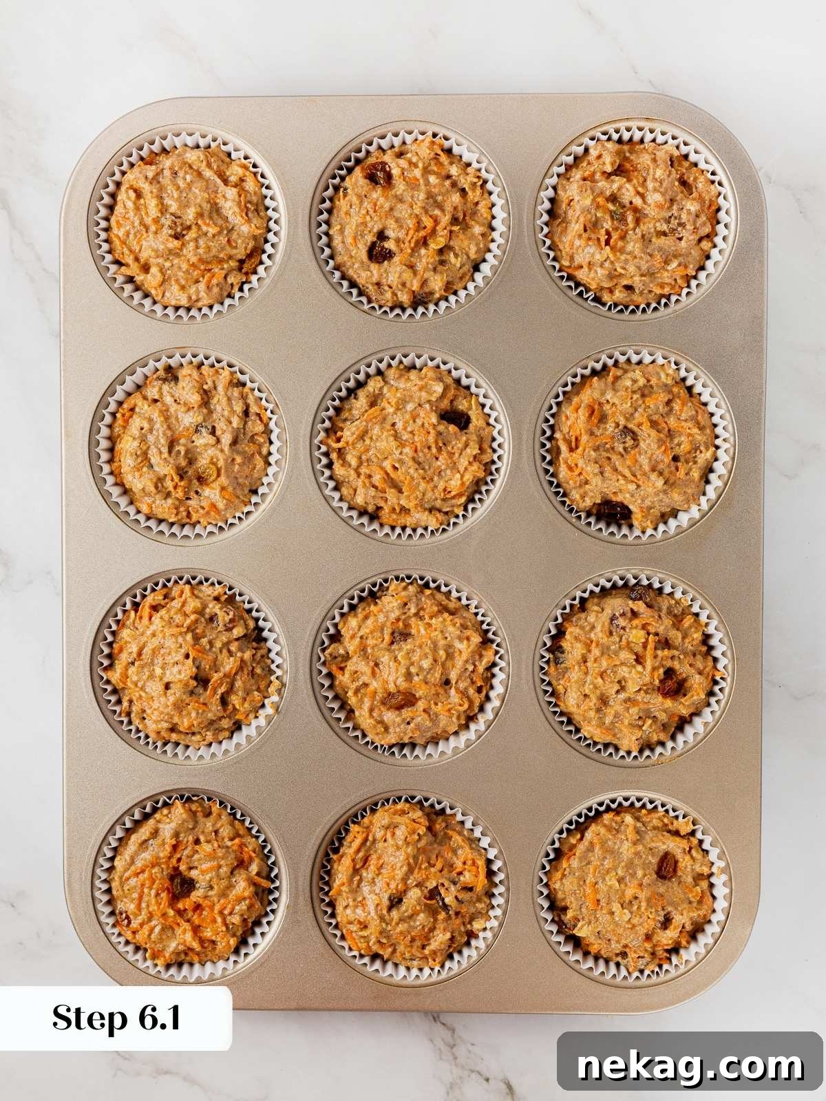 Healthy carrot muffin batter perfectly scooped into lined muffin cups, ready for baking.