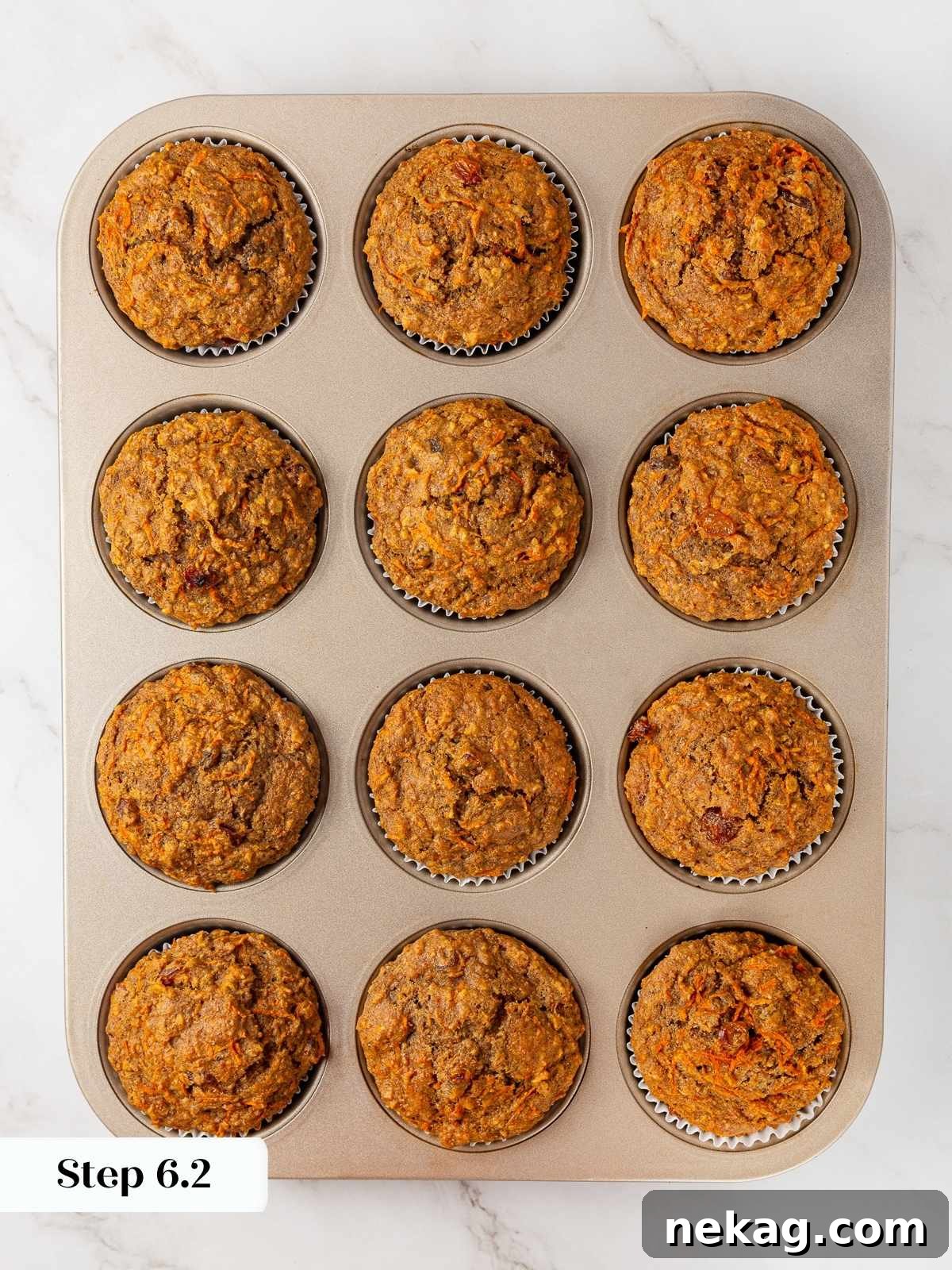 Freshly baked healthy carrot muffins in a muffin pan, just out of the oven, with golden brown tops.