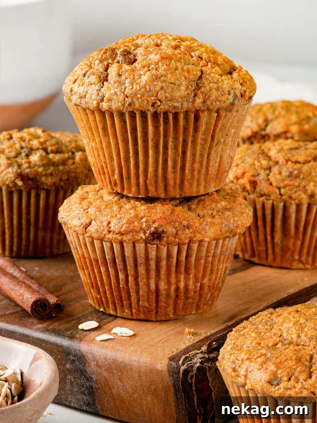 Two healthy carrot muffins stacked on a white plate, showcasing their golden tops and rustic, wholesome appearance.