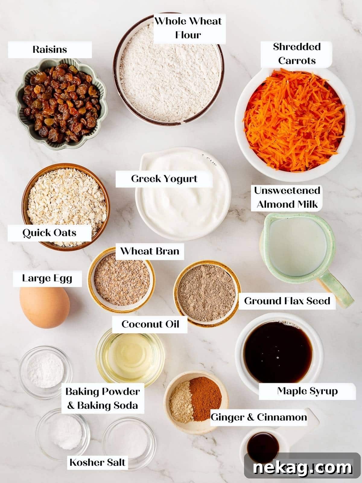 Various ingredients for healthy carrot muffins, including flour, oats, spices, and fresh carrots, neatly arranged on a kitchen counter.
