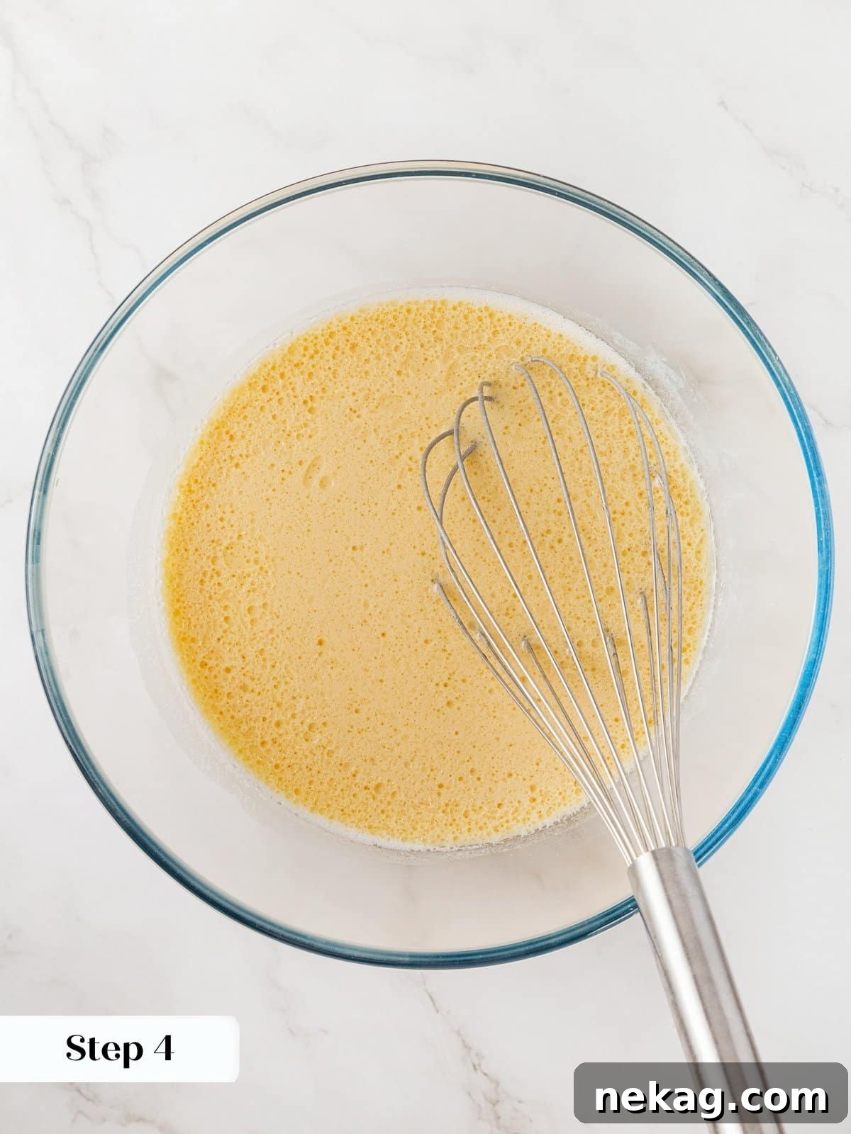 Melted coconut oil being gently added and whisked into the bowl of wet ingredients for the healthy carrot muffin batter, showing the mixture thickening slightly.