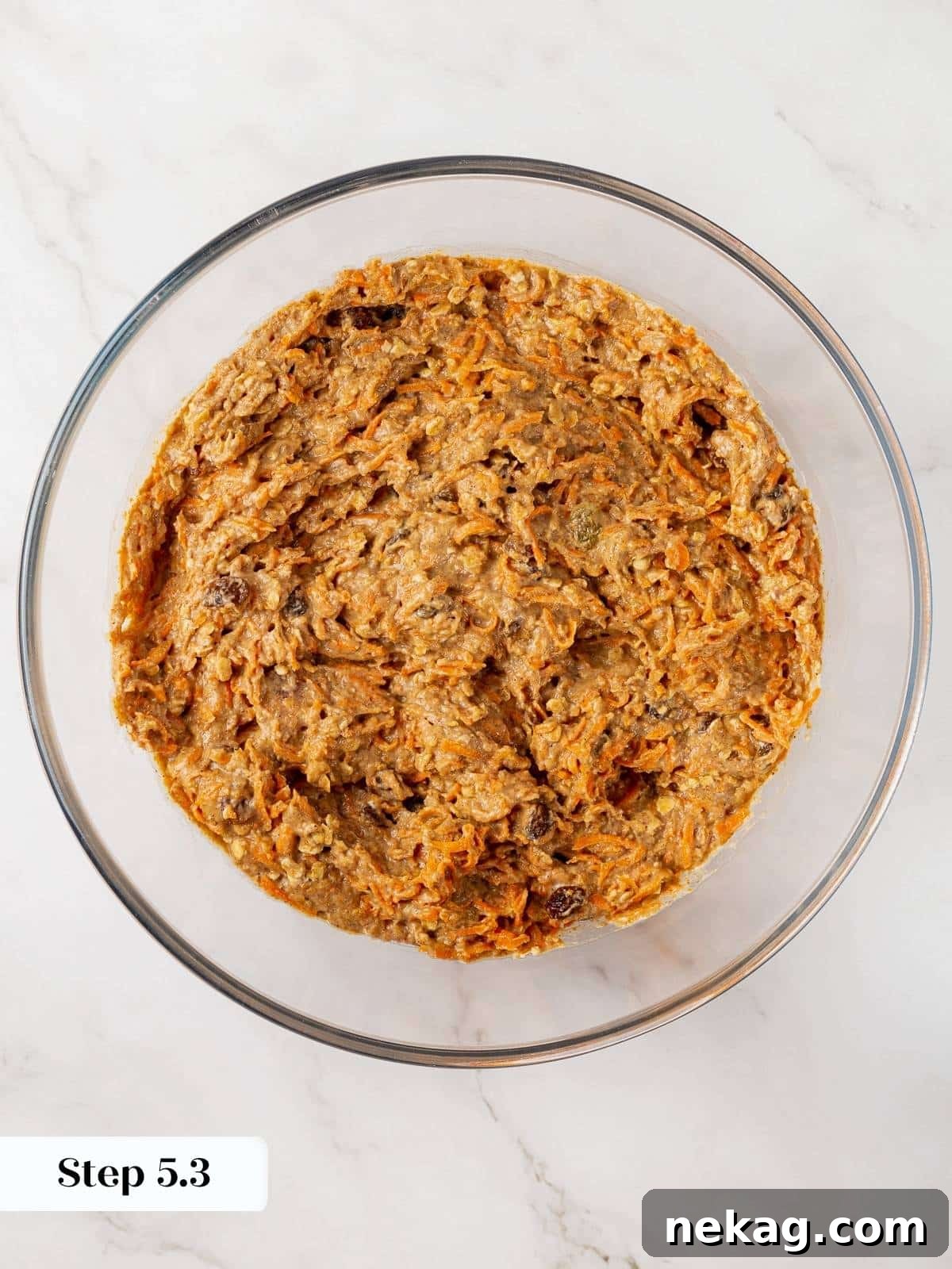 Final healthy carrot muffin batter with all ingredients, including grated carrots, thoroughly mixed in and ready for baking.