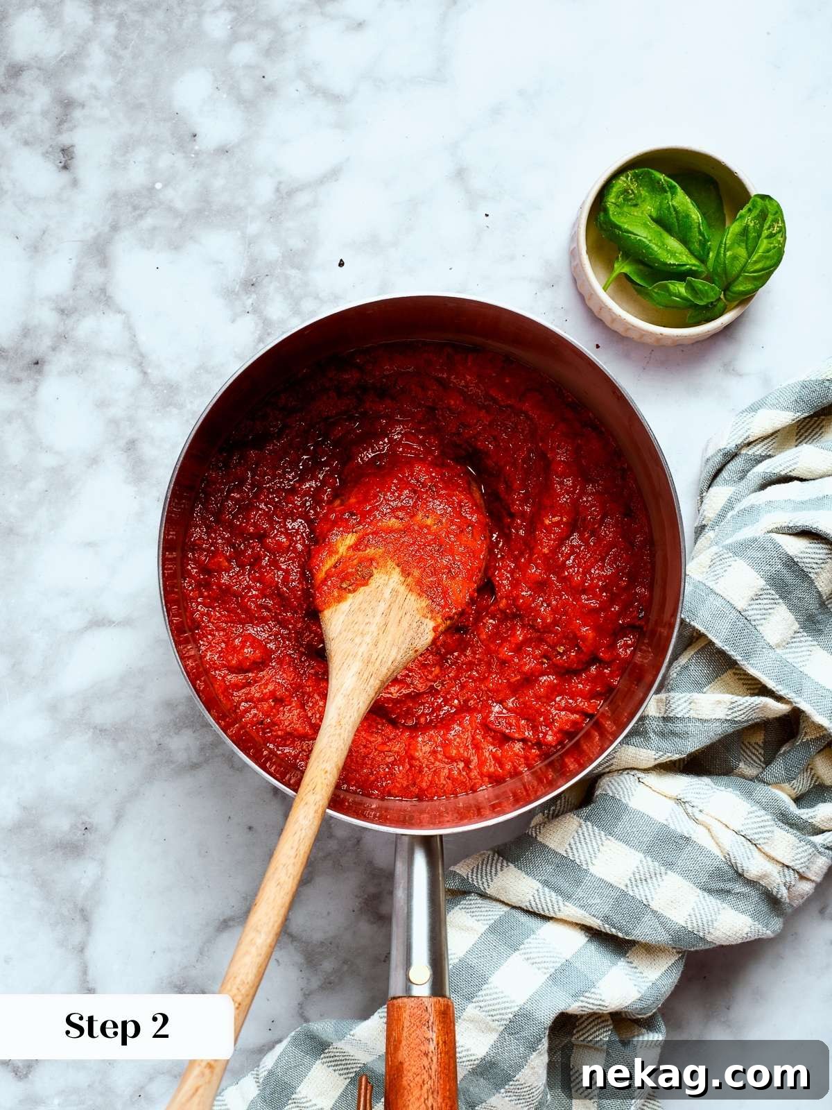 A wooden spoon stirring thickened, glossy tomato sauce in a saucepan, demonstrating the perfect consistency.
