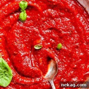 Rich tomato sauce clings to a spoon, ready to top a fresh crust for an unforgettable pizza.