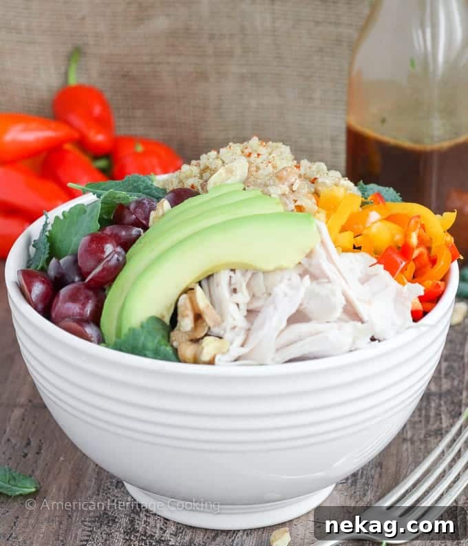 Supercharge Quinoa Kale Bowl 4 A close-up shot of the vibrant Quinoa Kale Power Bowl, showcasing fresh ingredients like roasted chicken, ripe avocado slices, colorful bell peppers, and juicy red grapes.