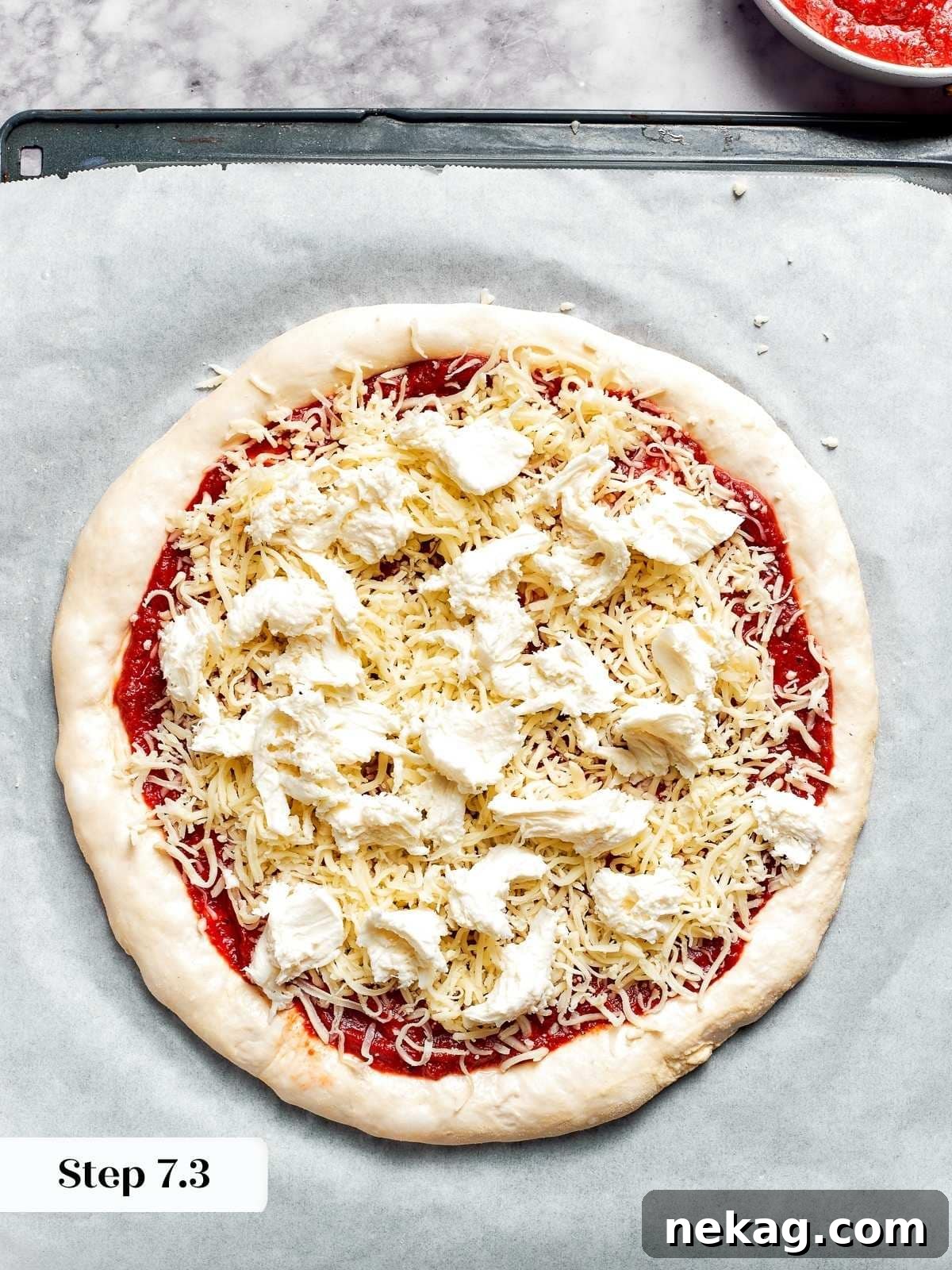 The final touch: topping the pizza dough with fresh mozzarella before it goes into the oven, ensuring a rich, gooey melt.