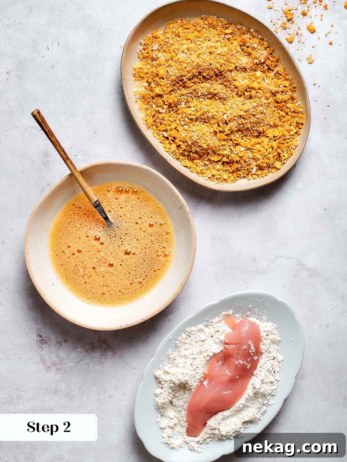 Crispy Air-Fried Chicken Fingers 5 Chicken tenders being coated in seasoned flour mixture on a plate during prep process.
