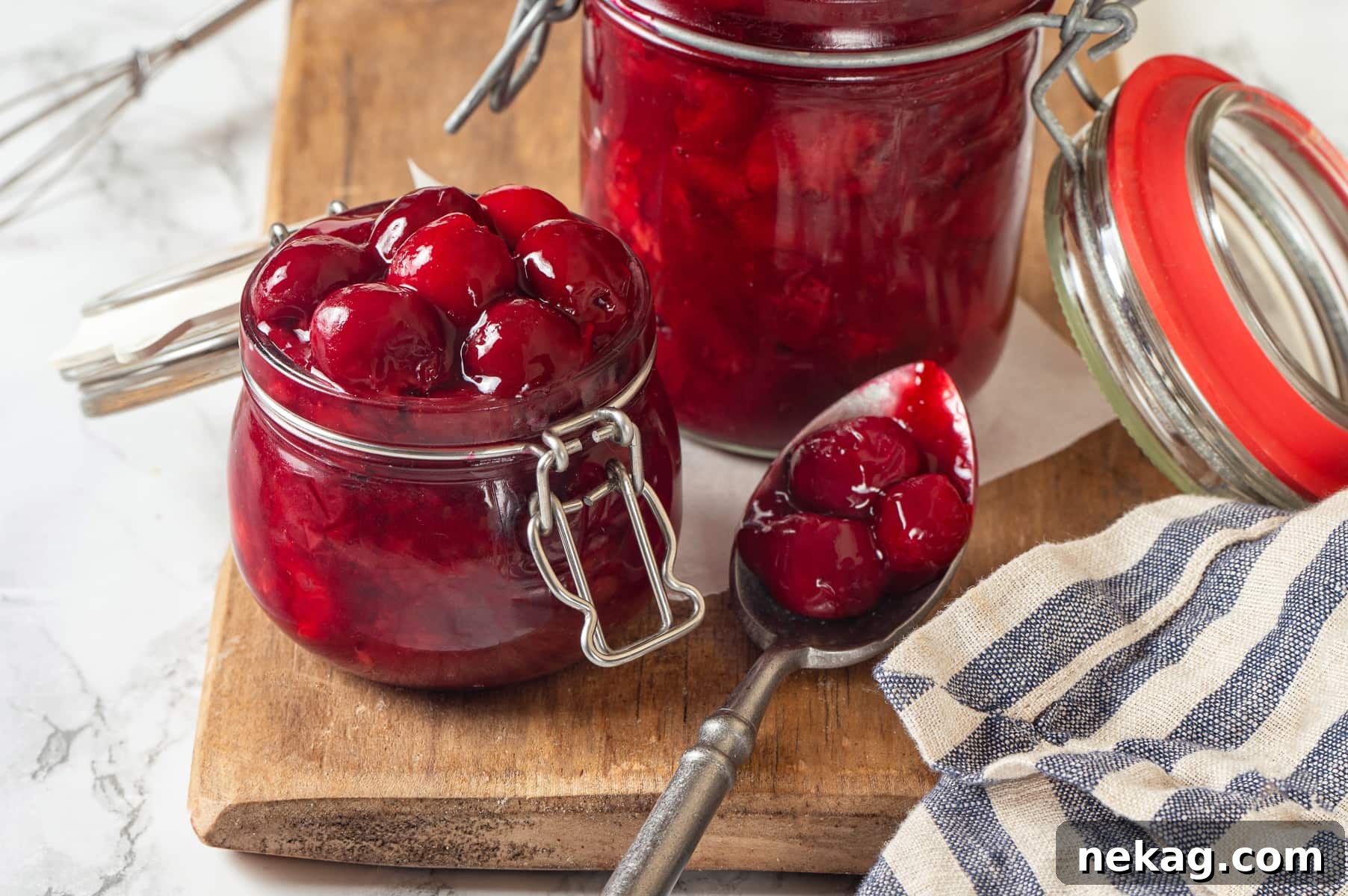 Thick, glossy cherry pie filling clings to spoon, showing texture and visible chunks of fruit.