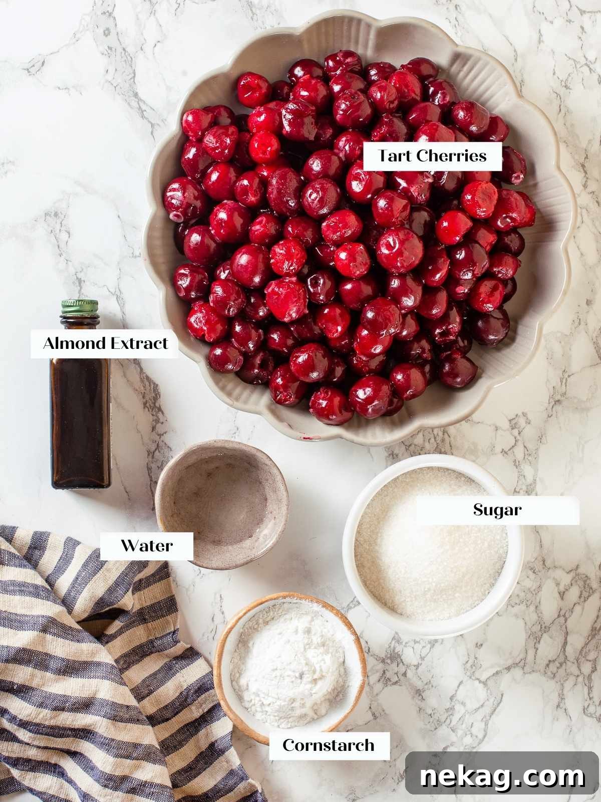 Ingredients for cherry pie filling laid out on counter, including cherries, sugar, and almond extract.