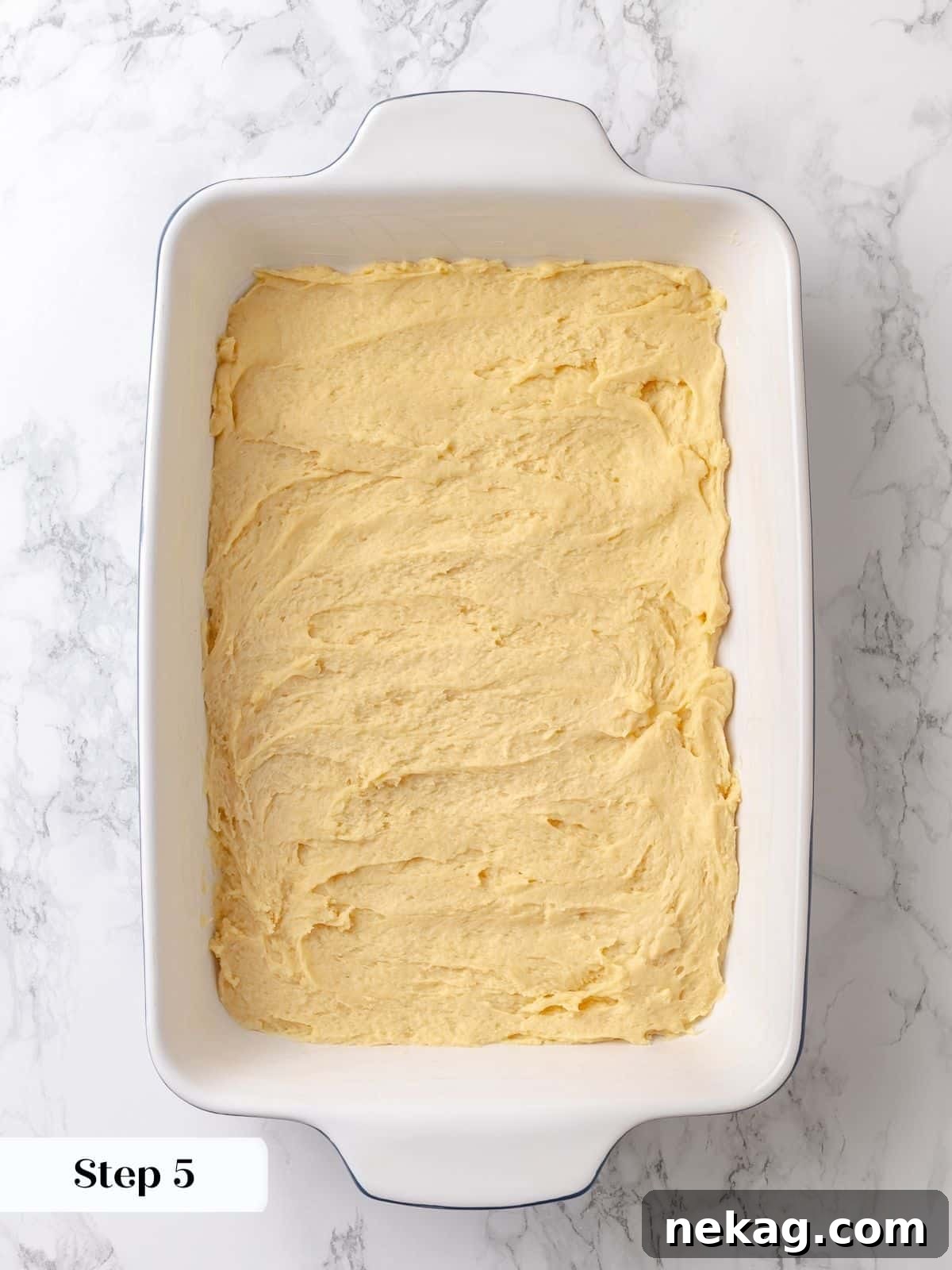 The cake dough has risen significantly in the pan, puffing slightly and indicating it's ready for the sweet sugar topping.