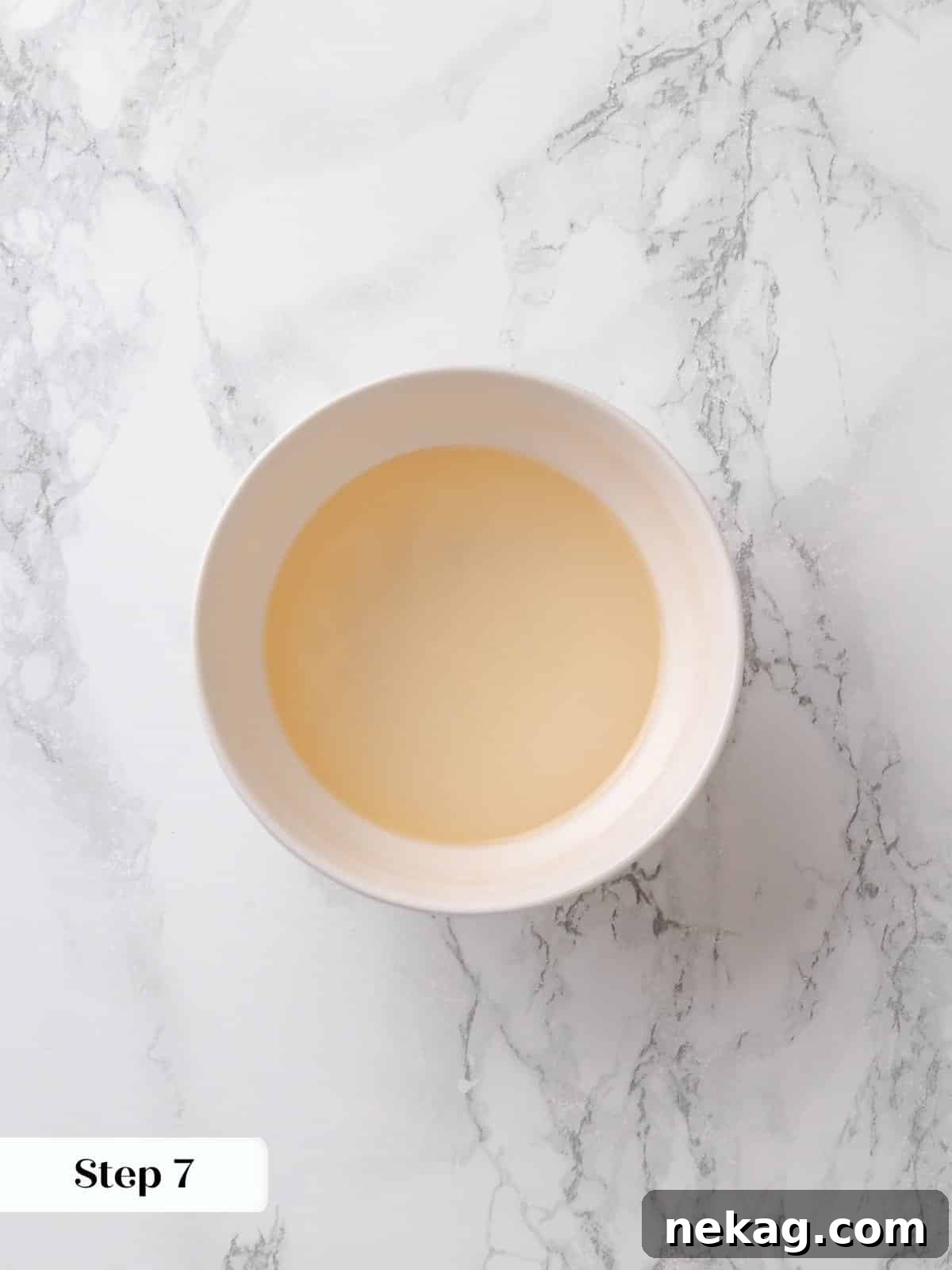 Corn syrup, water, and vanilla are whisked together to form a clear and well-combined syrup mixture, a crucial component for the topping.