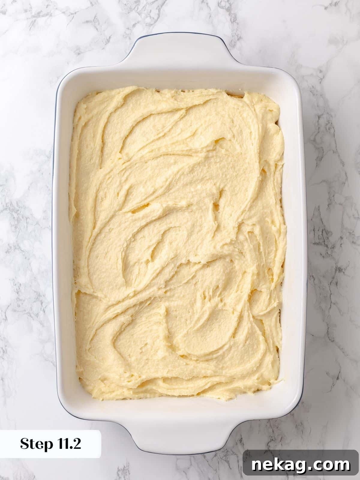 The rich, gooey topping layer is now fully covering the cake base, beautifully spread and ready to bake into its signature indulgent texture.