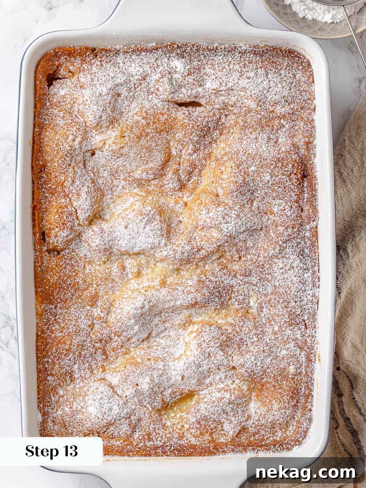A thick and even layer of powdered sugar is generously dusted on top of the baked gooey butter cake, ready for serving.
