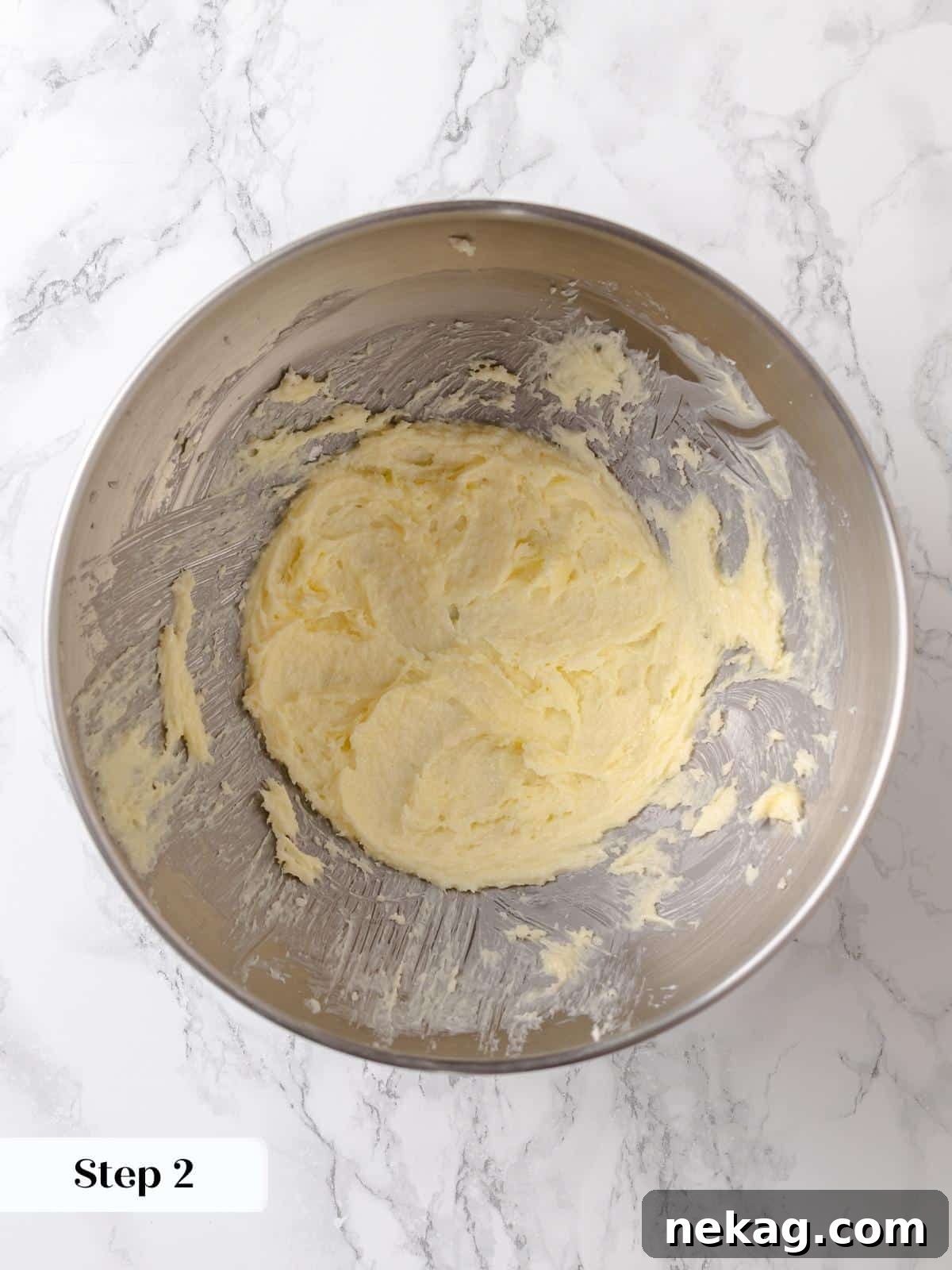 Butter and sugar mixture is creamed until lightened in color and fluffy, forming the foundational first step of the cake base.