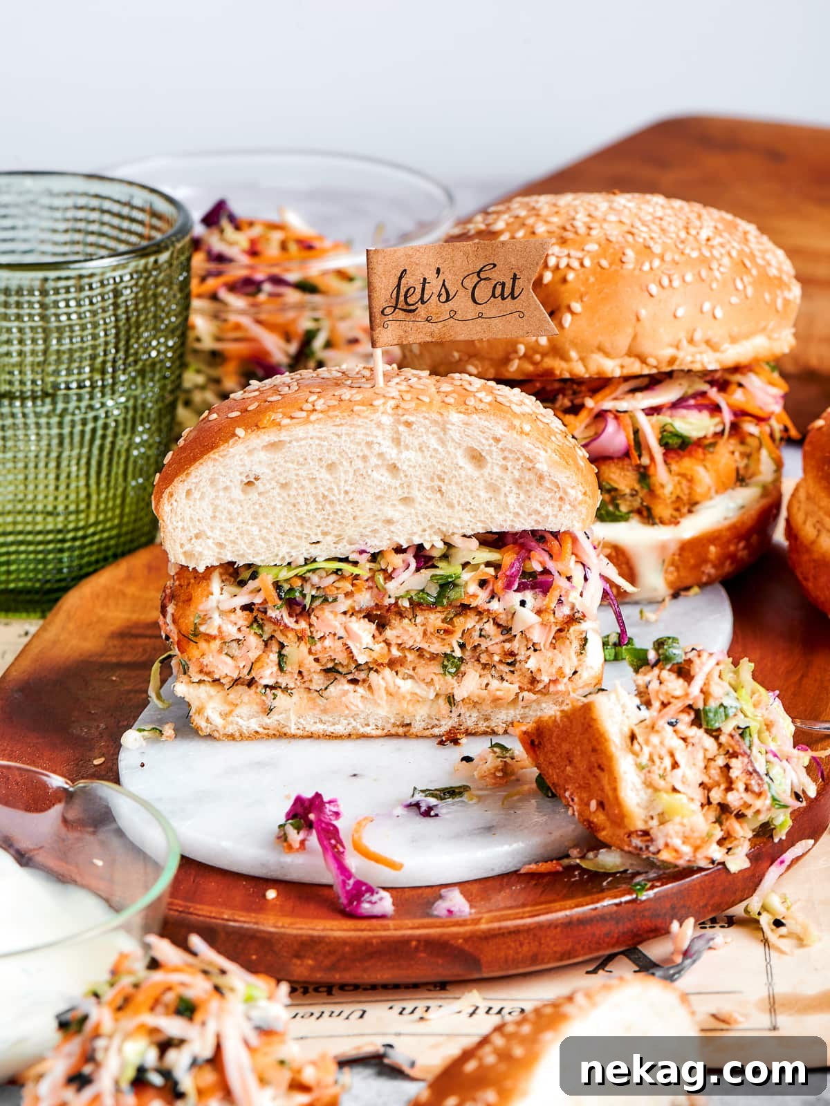 Hearty salmon burger with crisp slaw and sesame bun on a wooden serving dish.