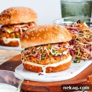 seasoned salmon patty showing fresh herbs and lemon zest inside assembled burger.