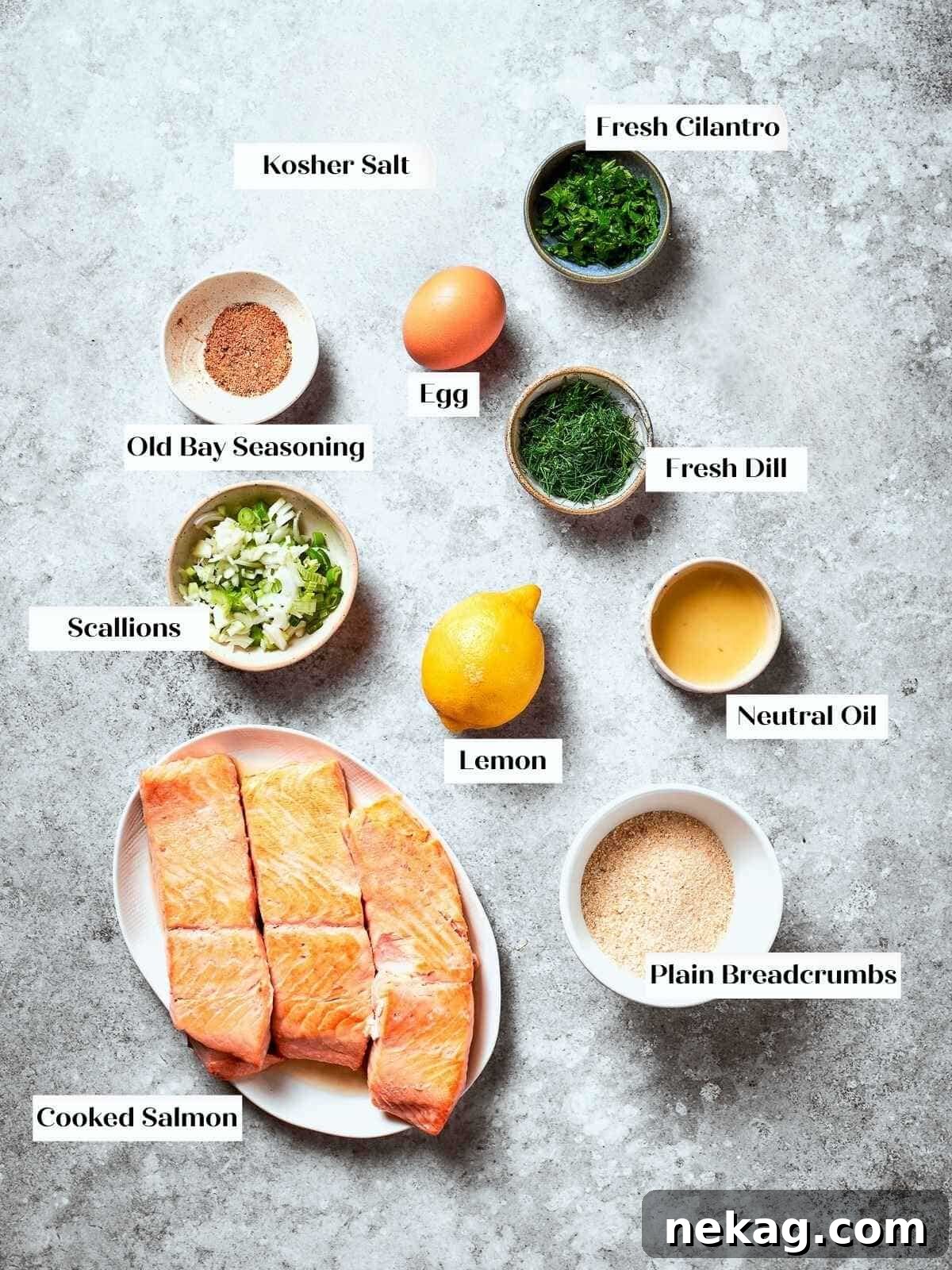 Prep station with ingredients like lemon, scallions, dill, and salmon for patty mixture.