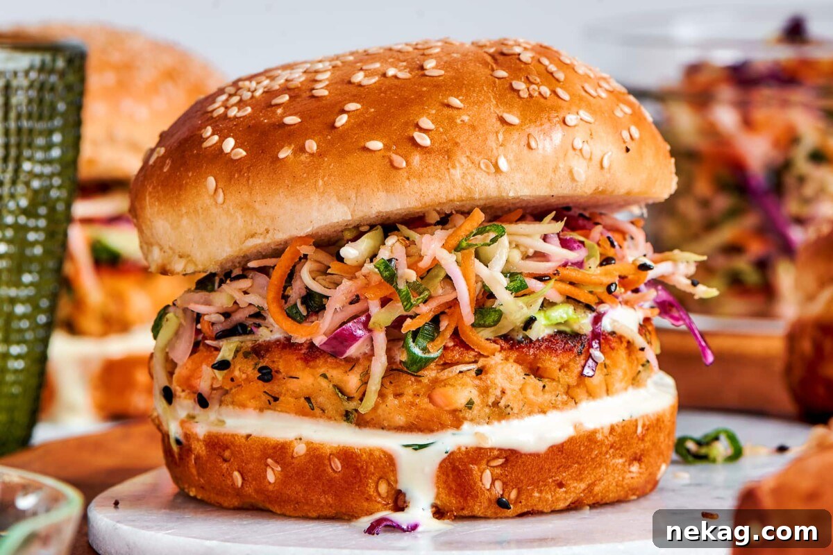 Fully assembled salmon burgers with slaw and sauce lined up and ready to eat.